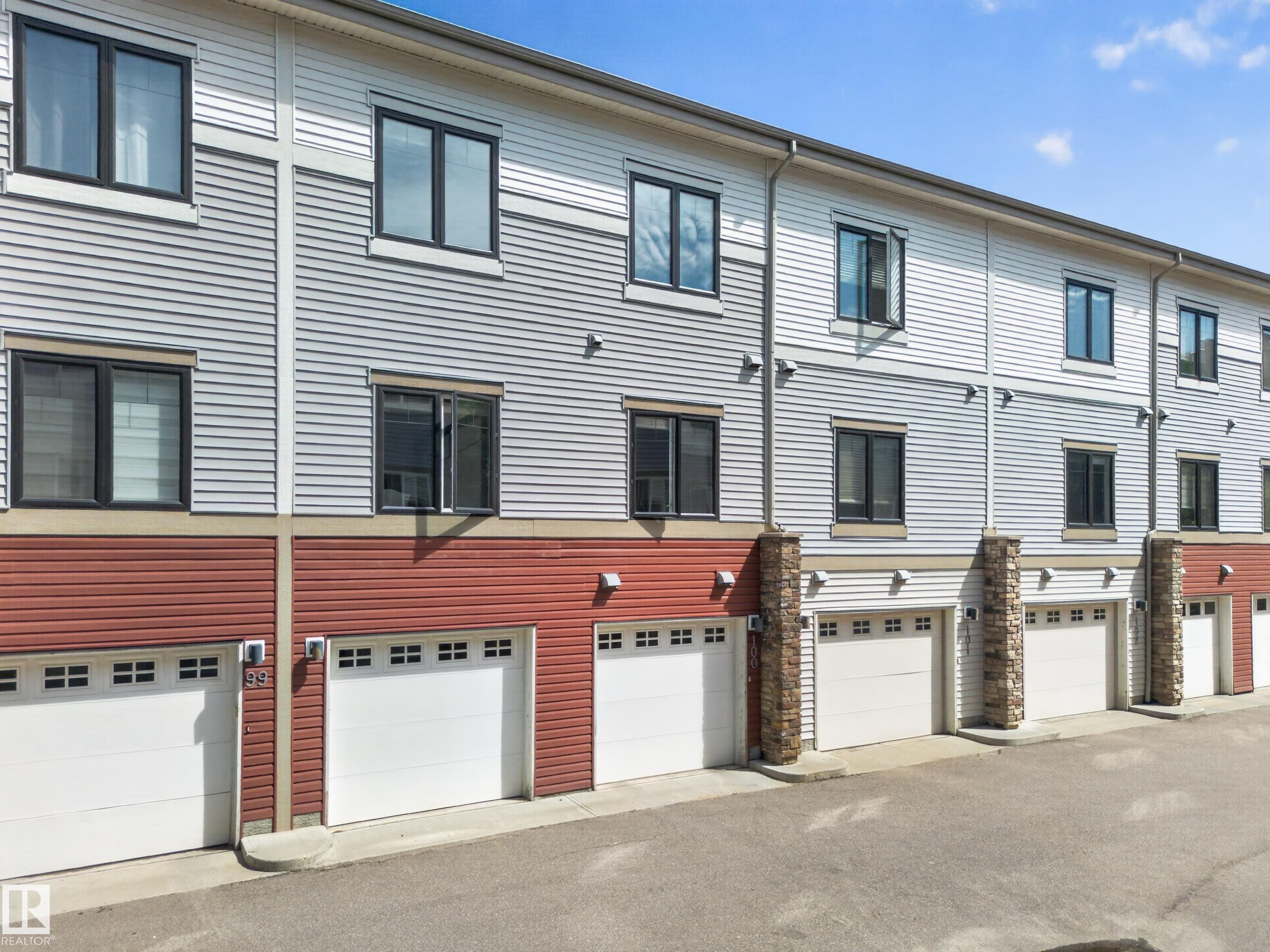 Multi-level townhome exterior featuring horizontal siding in light gray and red tones - #100 804 Welsh Dr Sw, Edmonton, AB - Outdoor