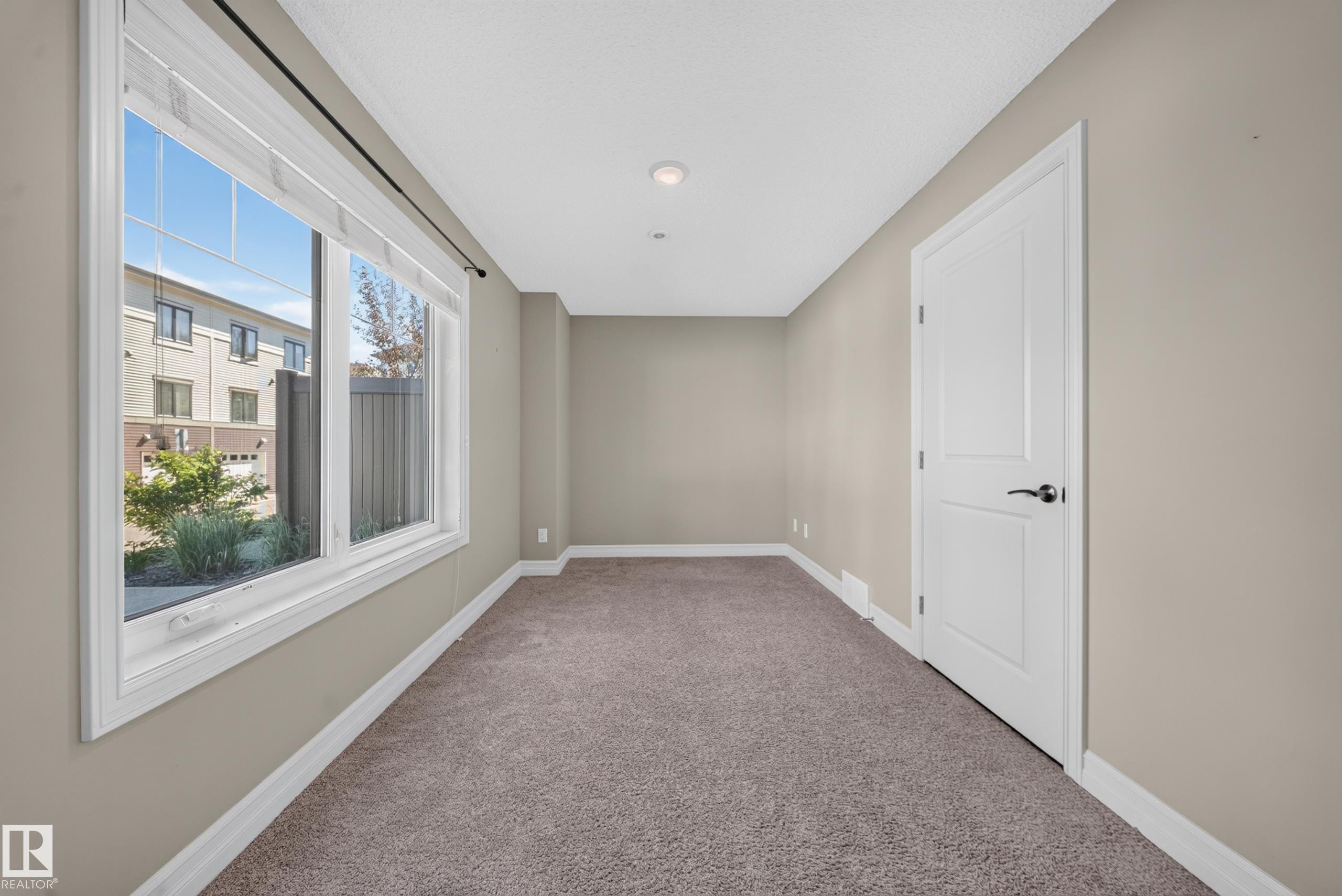 Room featuring a large window, neutral wall paint, white trim, and plush carpeting - #100 804 Welsh Dr Sw, Edmonton, AB - Indoor Photo Showing Other Room