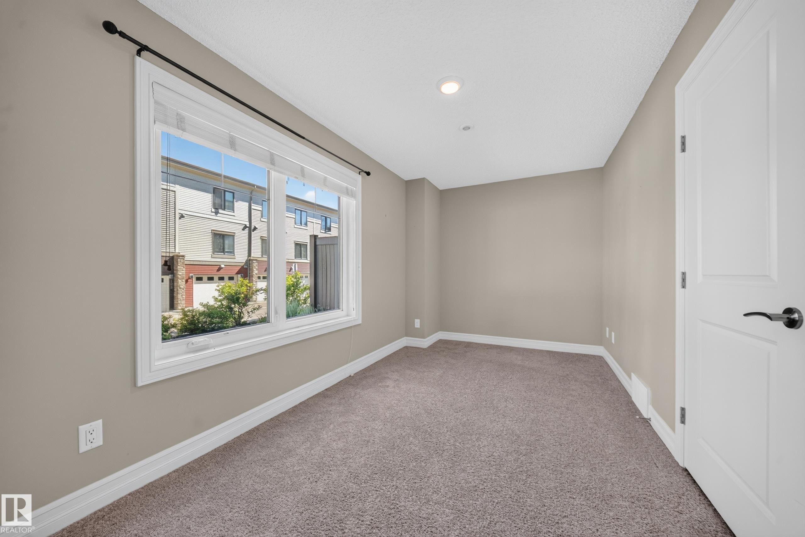 Neutral-toned room featuring a large window, recessed lighting, and soft carpet flooring - #100 804 Welsh Dr Sw, Edmonton, AB - Indoor Photo Showing Other Room