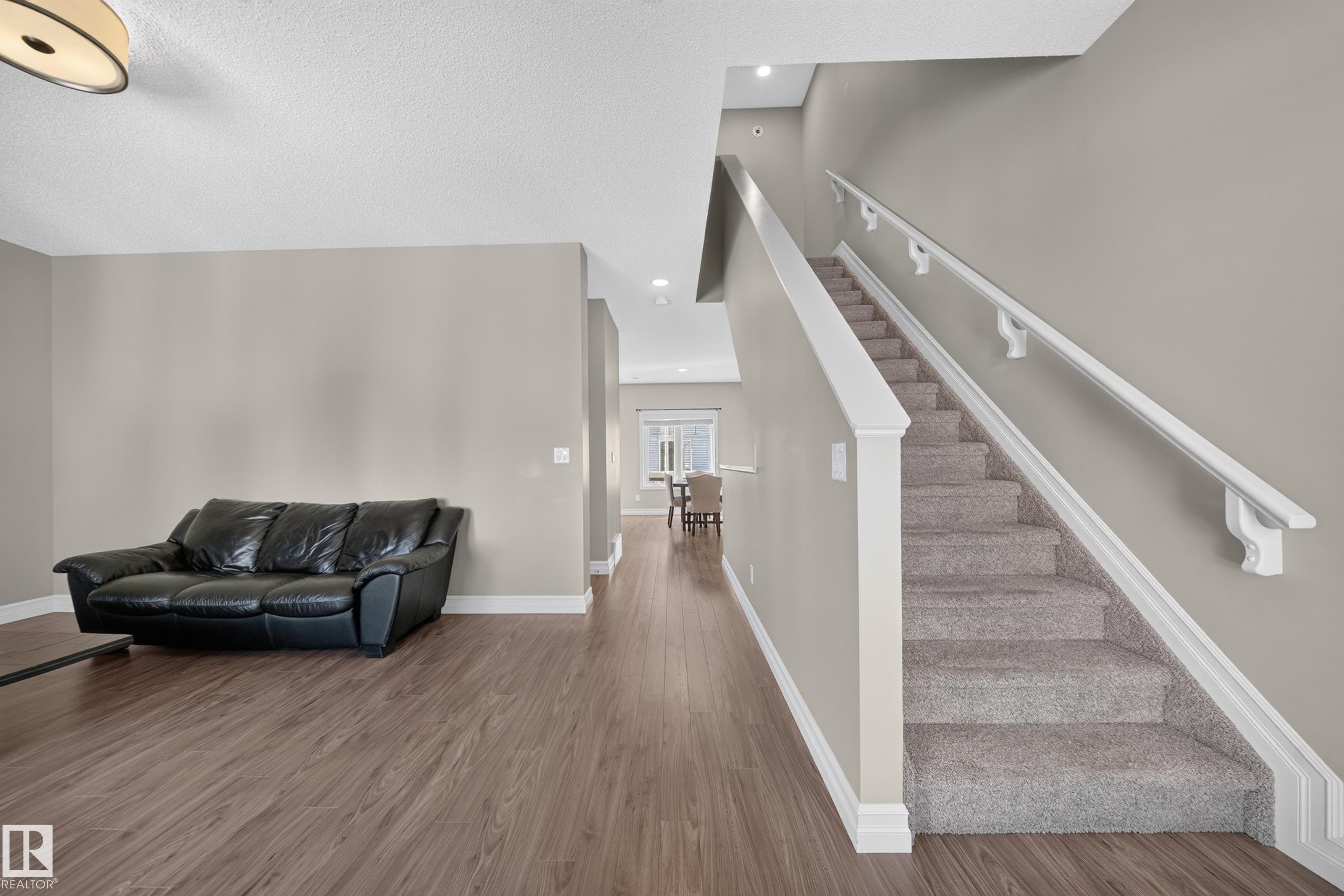Staircase with carpeted treads and white handrails, complemented by wood-finish flooring and neutral wall tones - #100 804 Welsh Dr Sw, Edmonton, AB - Indoor Photo Showing Other Room