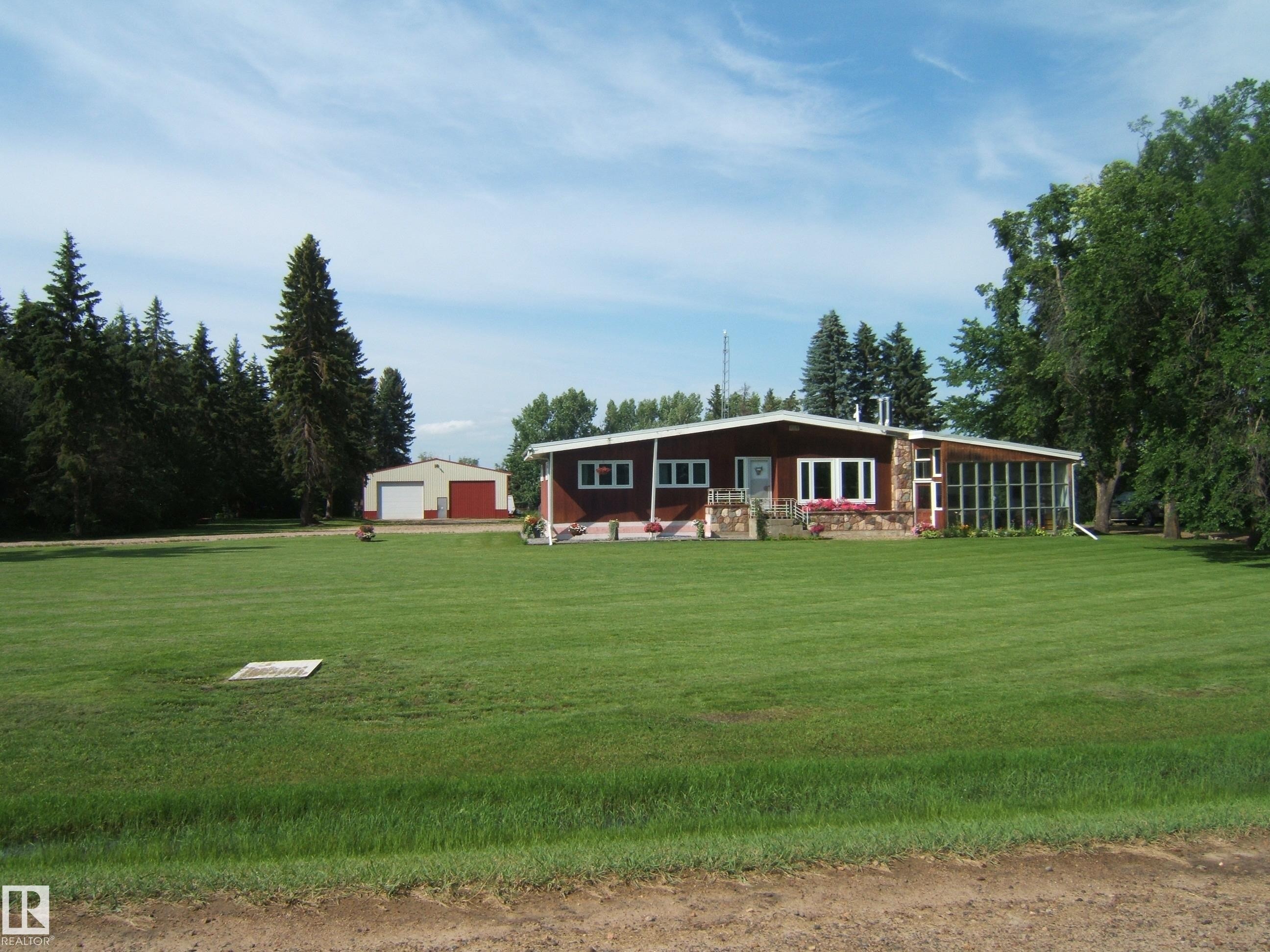 Ranch-style residence featuring a prominent stone facade accent and red siding - 151042 Twp Rd 562, Rural Two Hills County, AB - Outdoor