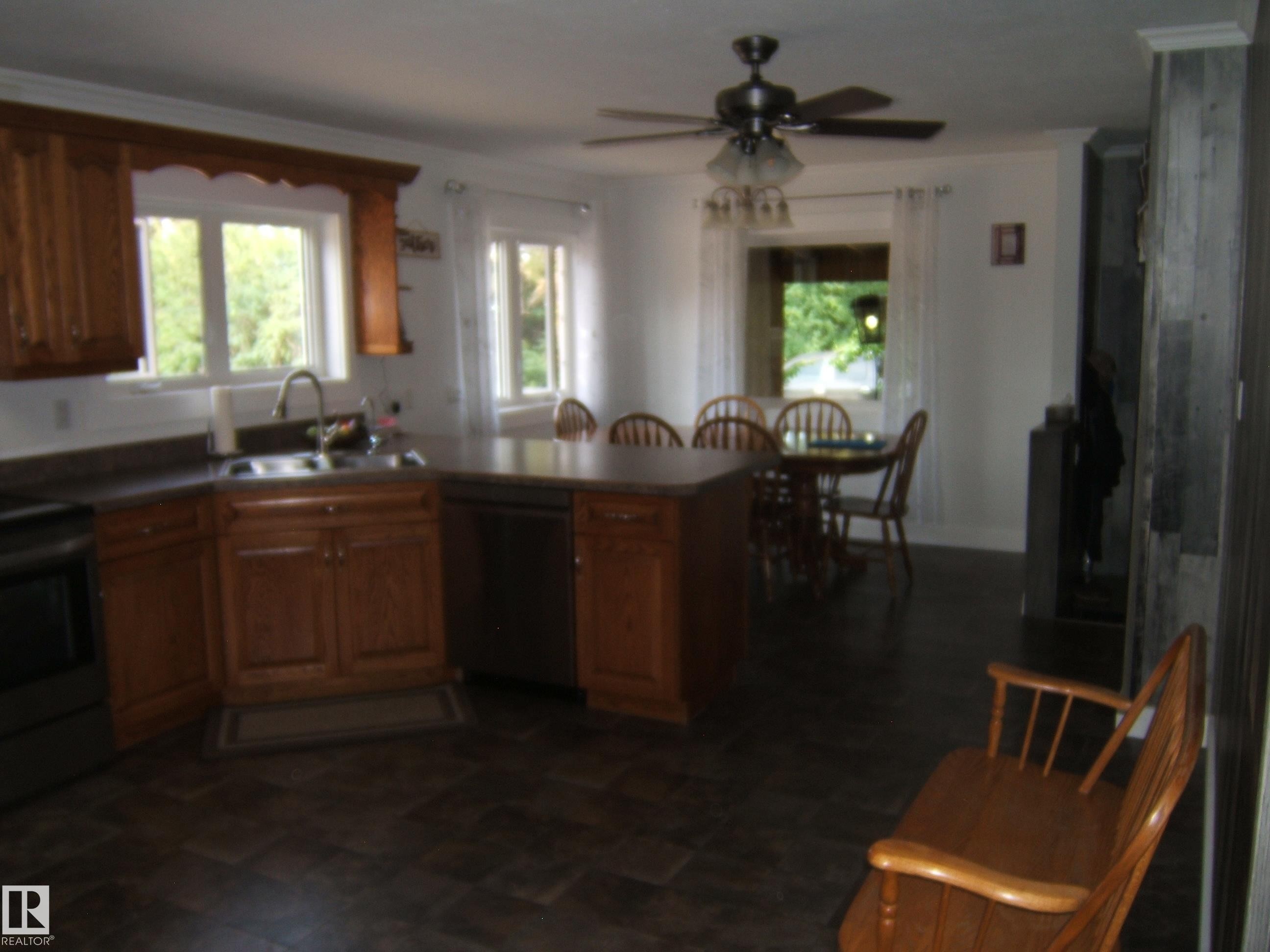 Kitchen featuring wood cabinetry, a stainless steel sink, and dark countertops - 151042 Twp Rd 562, Rural Two Hills County, AB - Indoor Photo Showing Other Room