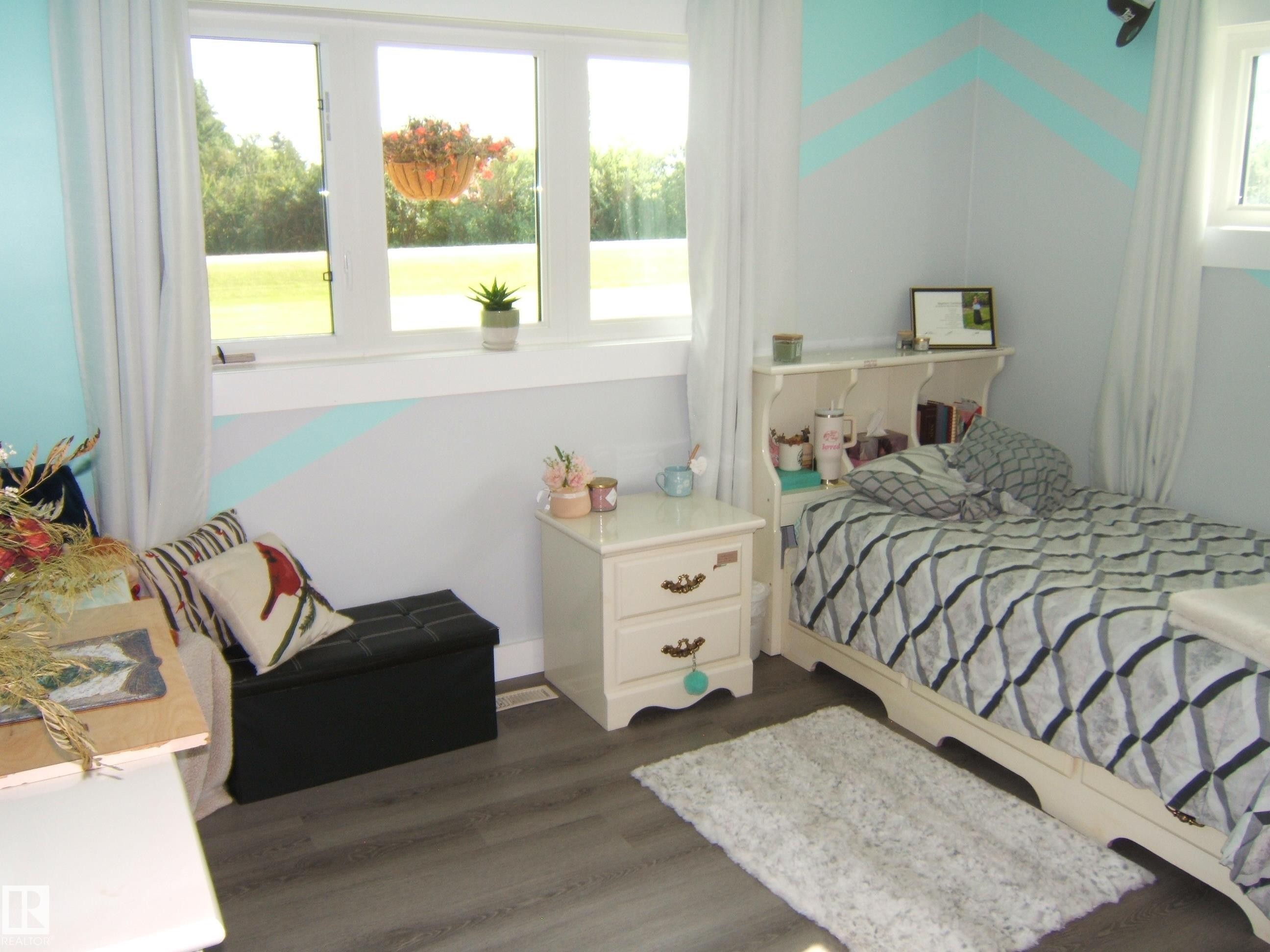 Room featuring wood-finish flooring, white trim, and light blue and gray wall accents - 151042 Twp Rd 562, Rural Two Hills County, AB - Indoor Photo Showing Bedroom
