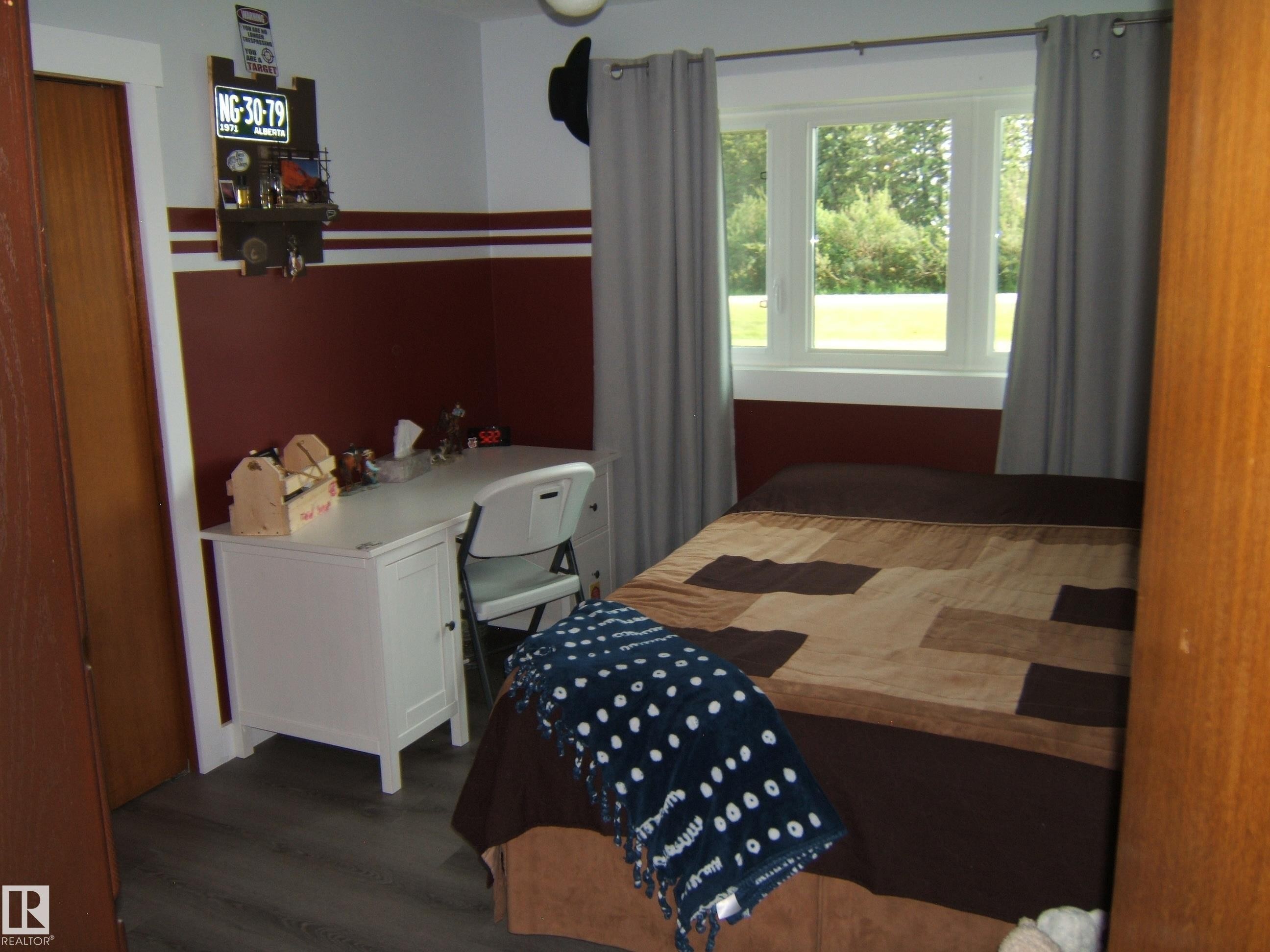 Space featuring contemporary wood-finish flooring, a white window frame, and a contrasting two-tone wall treatment - 151042 Twp Rd 562, Rural Two Hills County, AB - Indoor Photo Showing Bedroom
