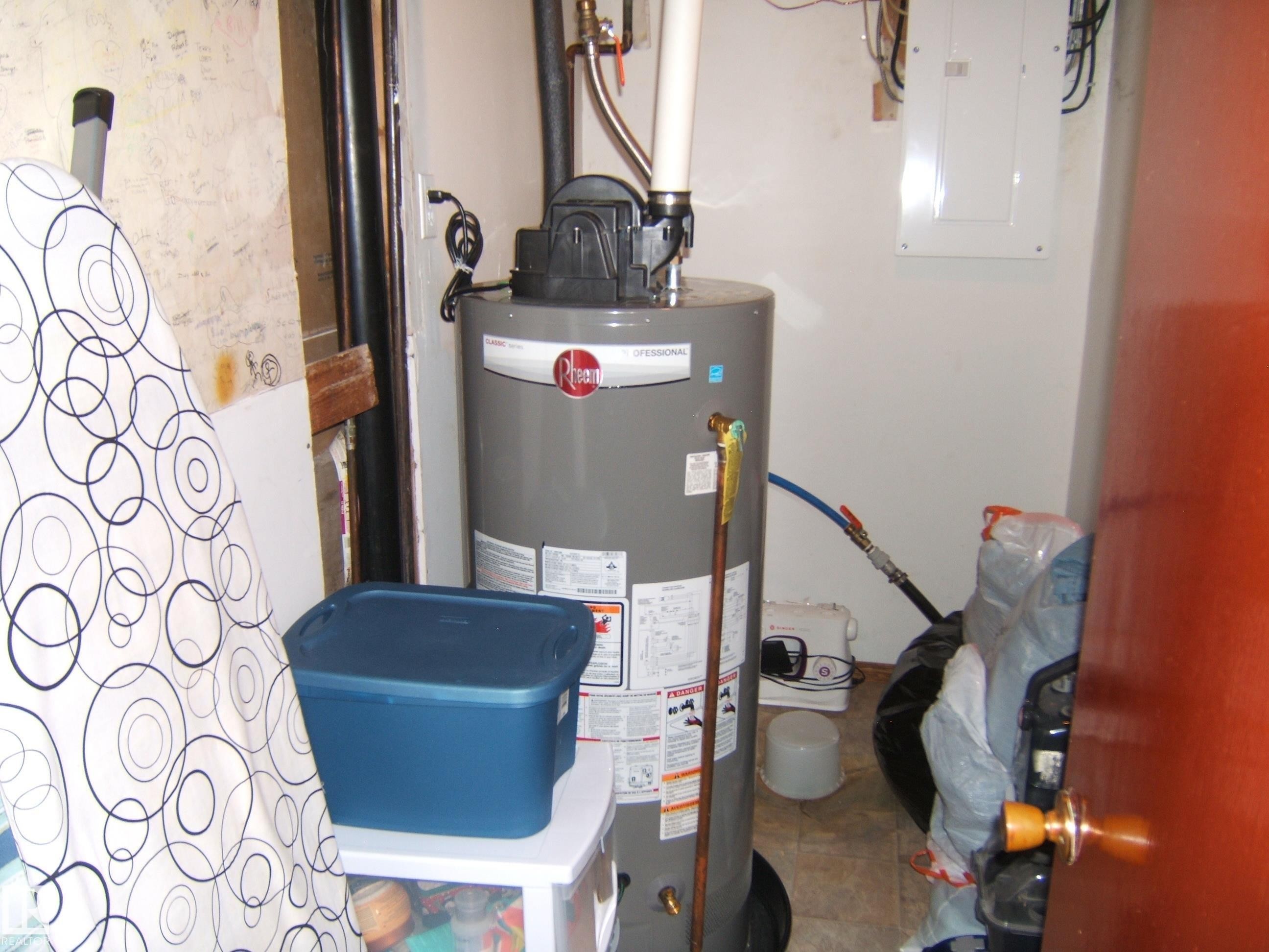 Utility area featuring a water heater, electrical service panel, and tile flooring - 151042 Twp Rd 562, Rural Two Hills County, AB - Indoor Photo Showing Basement