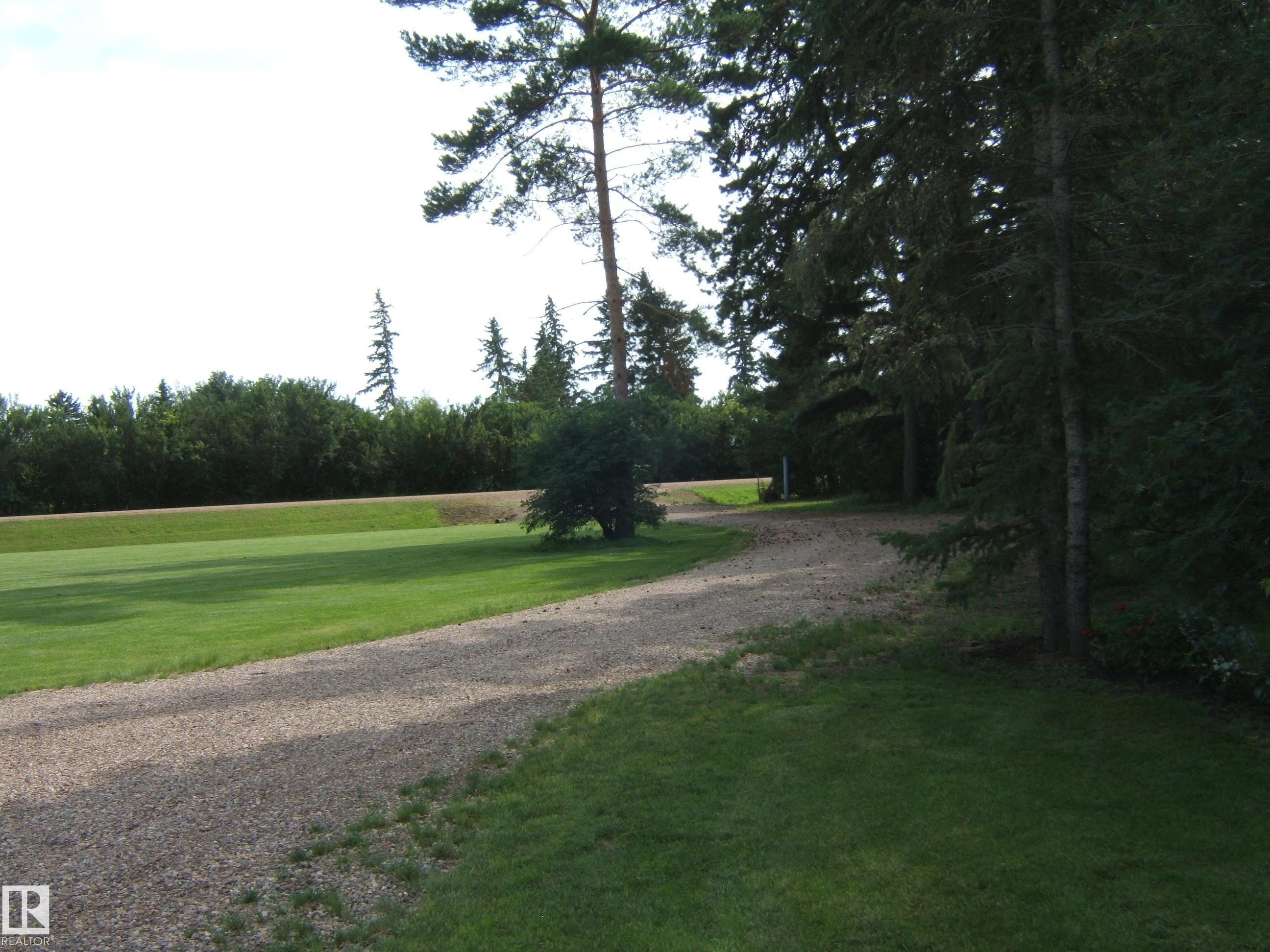 Extensive gravel driveway bordered by lush green lawns - 151042 Twp Rd 562, Rural Two Hills County, AB - Outdoor