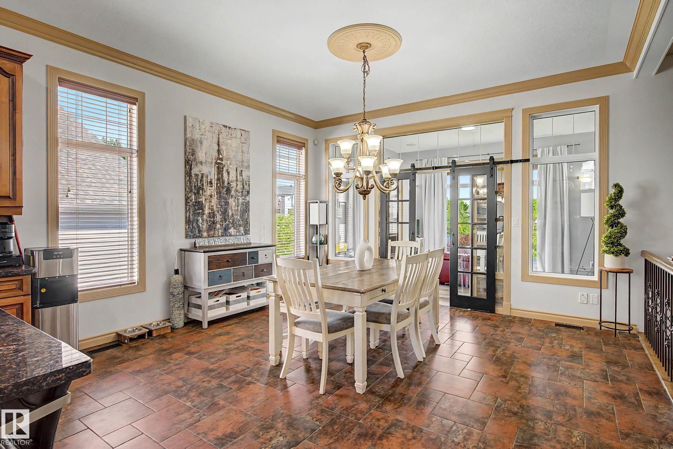 Dining area featuring wood-finish flooring, a decorative ceiling medallion with a brass chandelier, and multiple large windows with wood trim - 38 Longview Point(E), Spruce Grove, AB - Indoor Photo Showing Dining Room