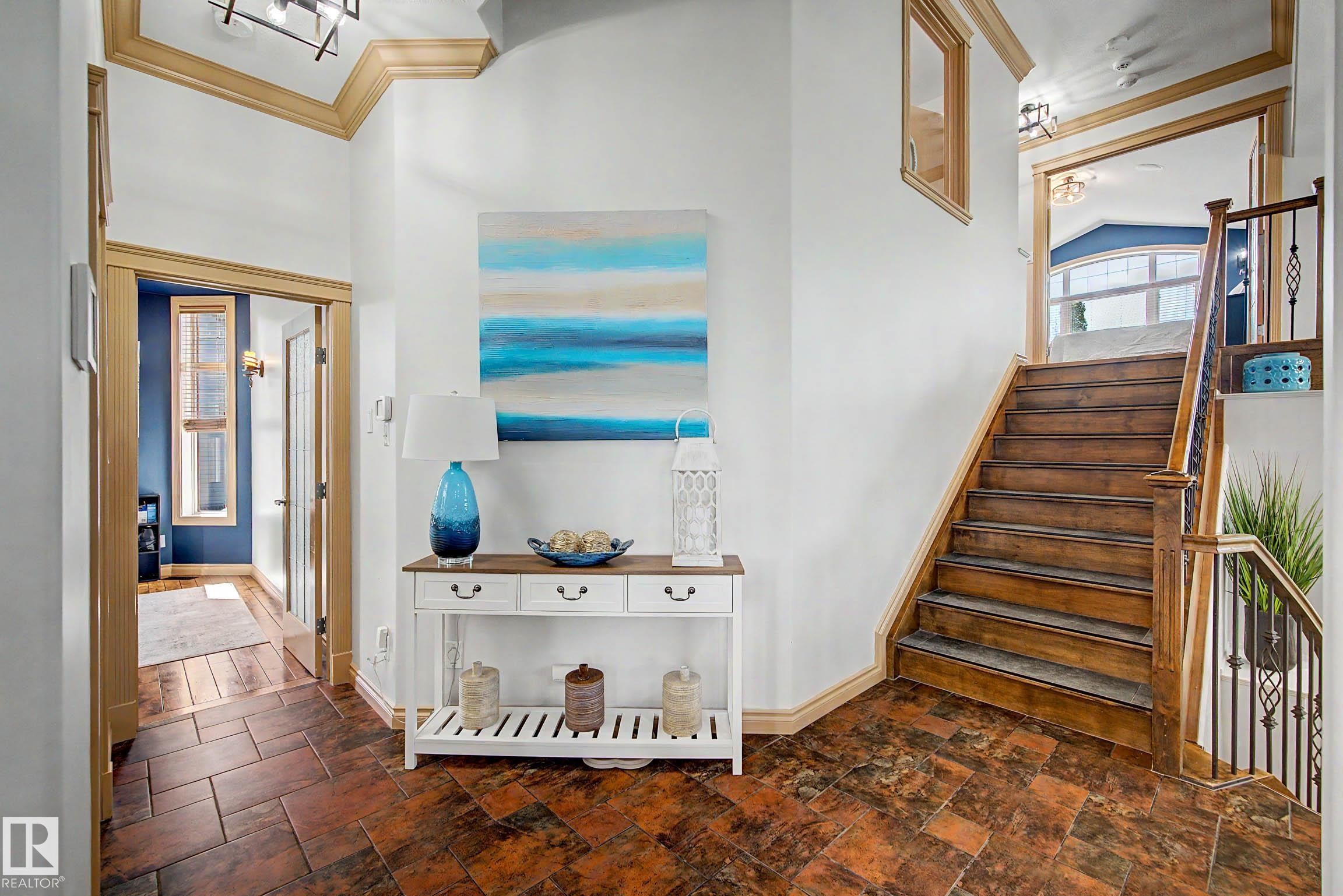 Entryway featuring wood-finish flooring, a staircase with wood treads and a wrought iron railing, and architectural trim details - 38 Longview Point(E), Spruce Grove, AB - Indoor Photo Showing Other Room