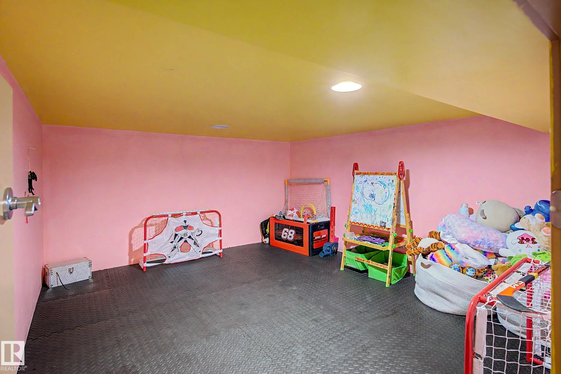 Lower level recreation space featuring resilient black flooring, vibrant pink walls, and a recessed ceiling light - 38 Longview Point(E), Spruce Grove, AB - Indoor