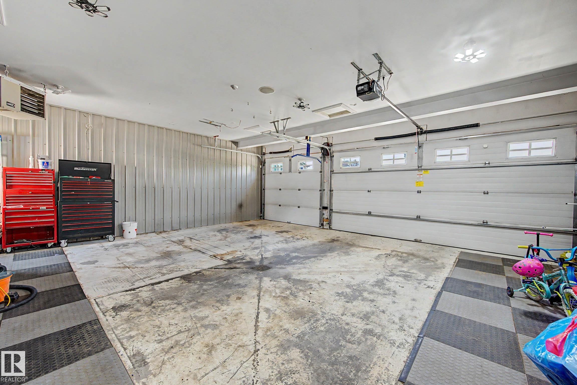 Spacious garage featuring two overhead doors with window inserts and automatic openers - 38 Longview Point(E), Spruce Grove, AB - Indoor Photo Showing Garage