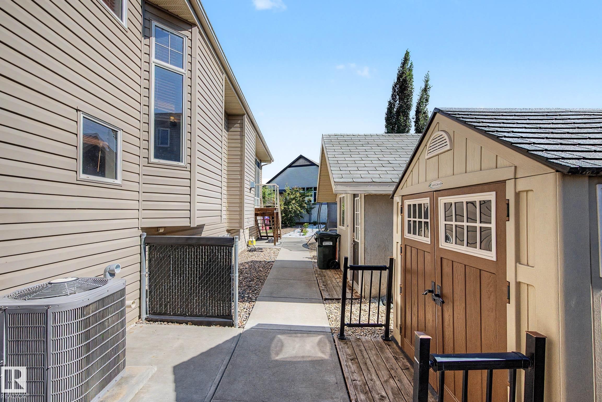 Two-tone storage shed with a shingled roof and double doors featuring window accents - 38 Longview Point(E), Spruce Grove, AB - Outdoor With Exterior