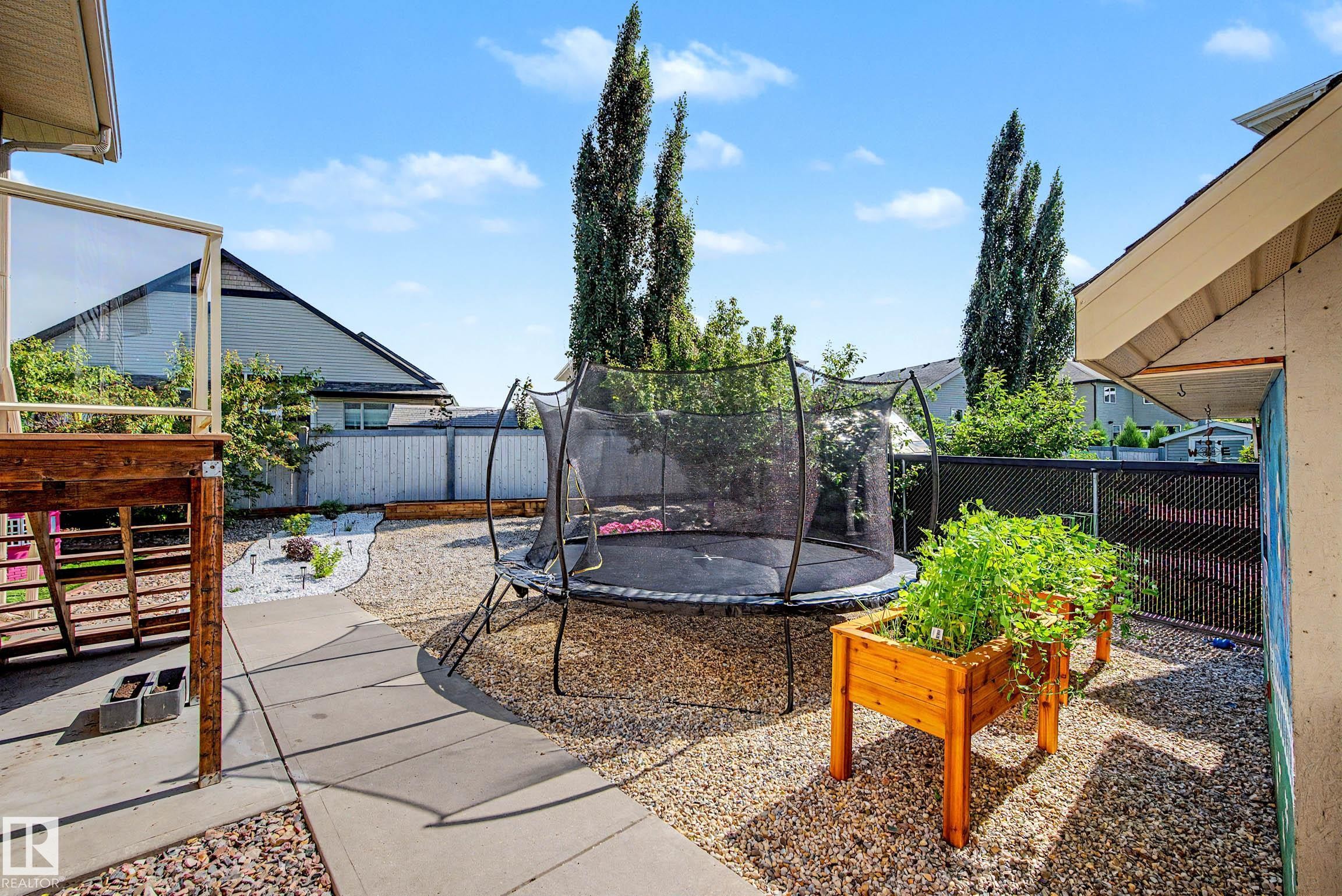 Backyard featuring a concrete patio, gravel landscaping, a raised wooden planter, and a privacy fence - 38 Longview Point(E), Spruce Grove, AB - Outdoor With Exterior