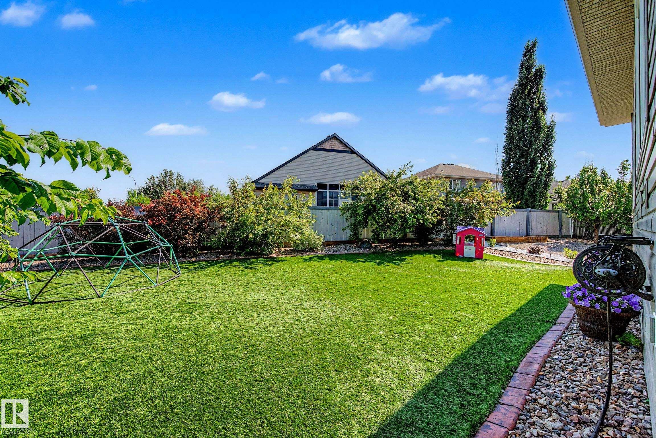 Expansive green lawn with established perimeter landscaping and a border of brick pavers and decorative rock - 38 Longview Point(E), Spruce Grove, AB - Outdoor