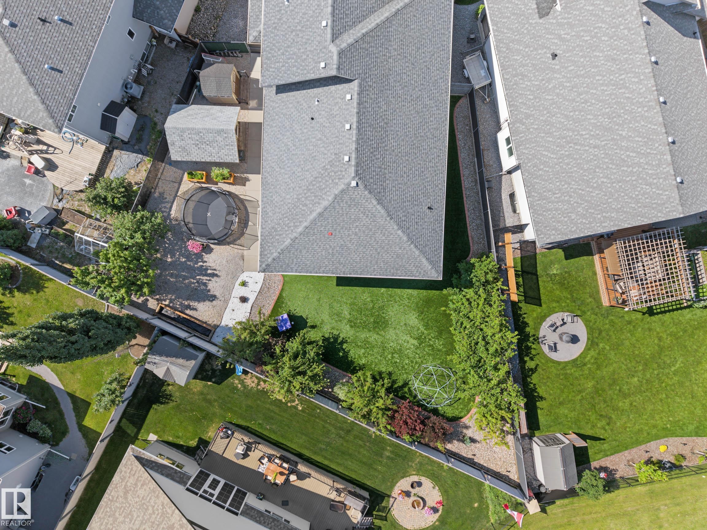 Expansive backyard featuring a manicured lawn, mature trees, and a concrete patio - 38 Longview Point(E), Spruce Grove, AB - Outdoor With View