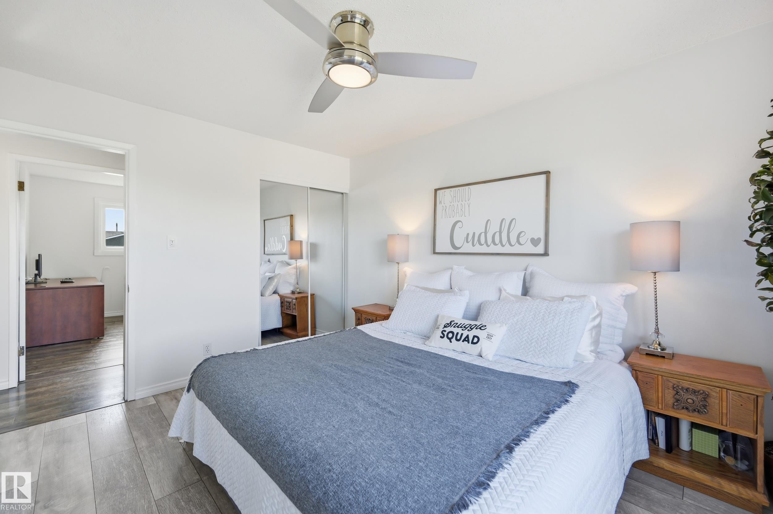 Bedroom featuring wood-finish flooring, a contemporary ceiling fan, and built-in mirrored closet doors - 15111 67 Street Nw, Edmonton, AB - Indoor Photo Showing Bedroom