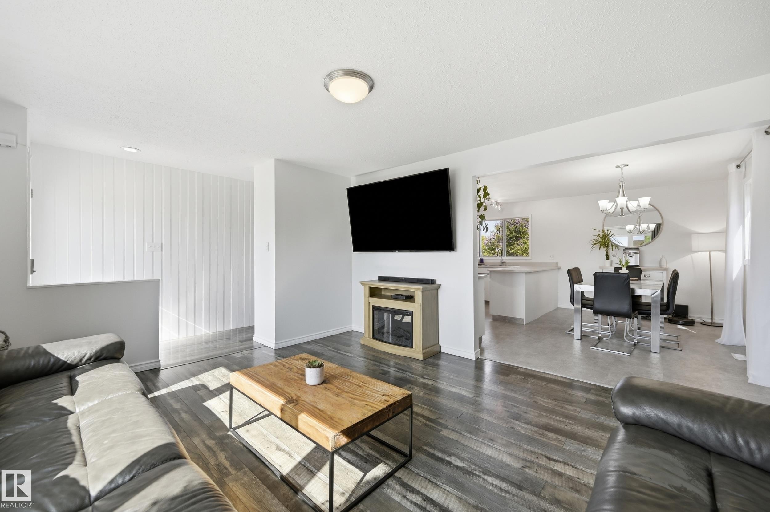 Spacious living area featuring wood-finish flooring, a contemporary fireplace unit, and an open concept layout - 15111 67 Street Nw, Edmonton, AB - Indoor Photo Showing Living Room
