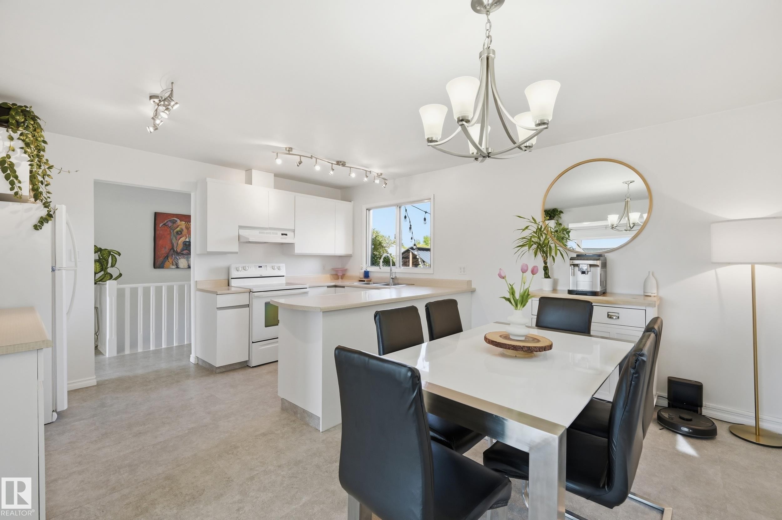 Open-concept kitchen and dining area featuring light-toned flooring, white cabinetry, a kitchen island, and a window providing natural light - 15111 67 Street Nw, Edmonton, AB - Indoor