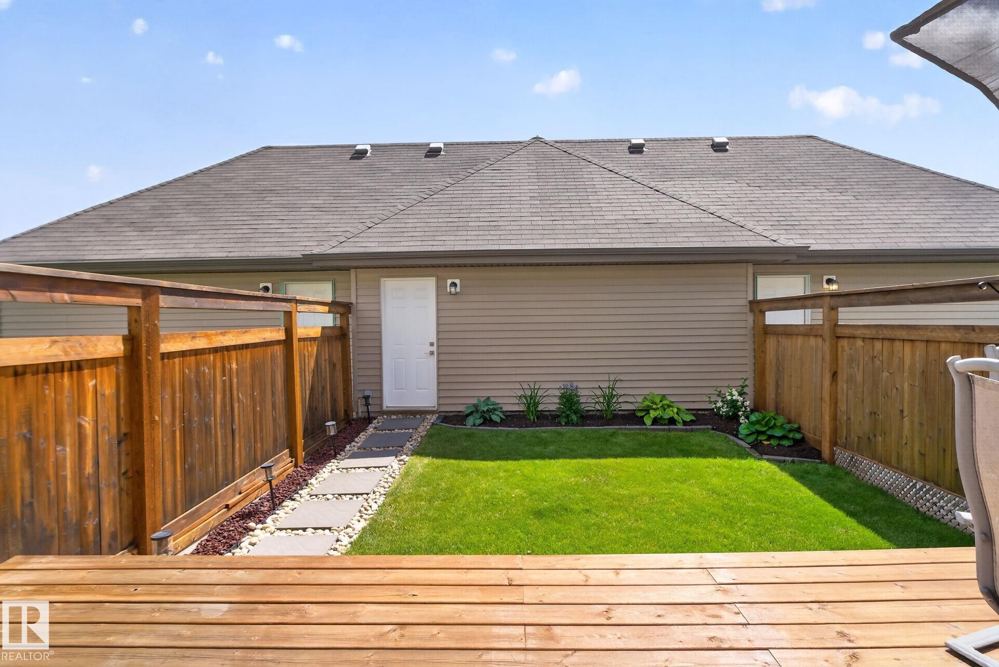 Private backyard featuring a wooden deck, a manicured lawn, and a stepping stone path - 319 Desrochers Boulevard Sw, Edmonton, AB - Outdoor With Exterior