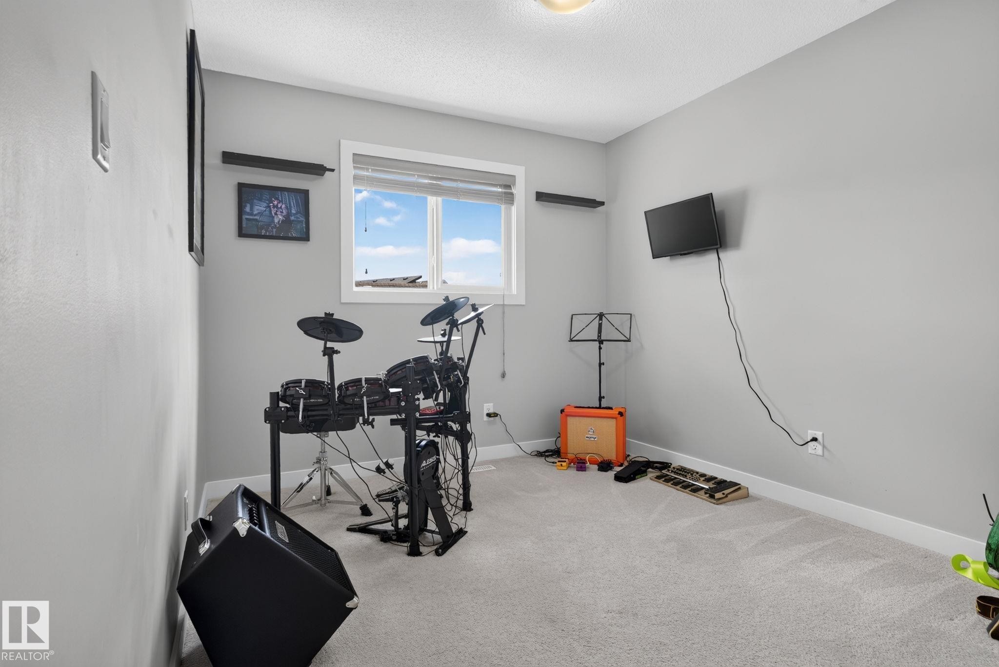 Room featuring a window, light gray painted walls, and light-colored carpet flooring - 319 Desrochers Boulevard Sw, Edmonton, AB - Indoor Photo Showing Gym Room