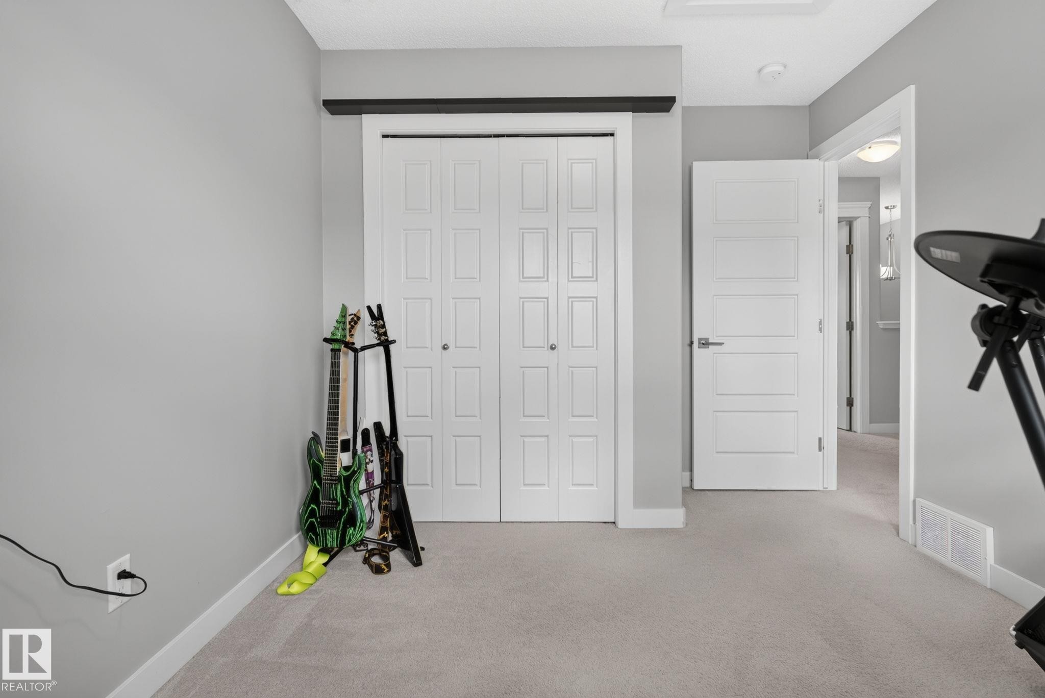 Neutral-toned room featuring a closet with bi-fold paneled doors, light grey wall paint, white trim, and light-colored carpeting - 319 Desrochers Boulevard Sw, Edmonton, AB - Indoor