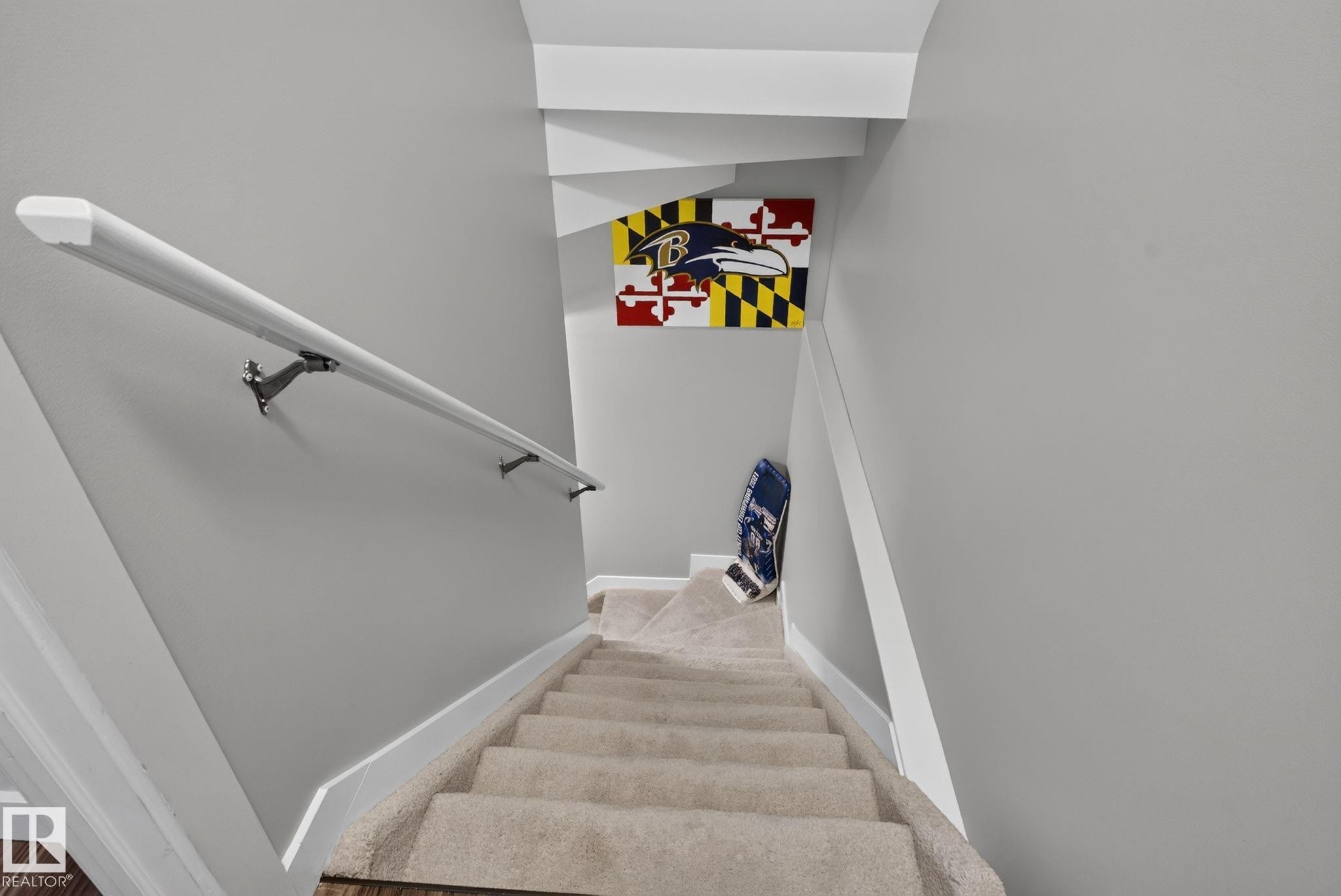 Carpeted staircase with light gray walls, white trim, and a white handrail with metal brackets - 319 Desrochers Boulevard Sw, Edmonton, AB - Indoor Photo Showing Other Room
