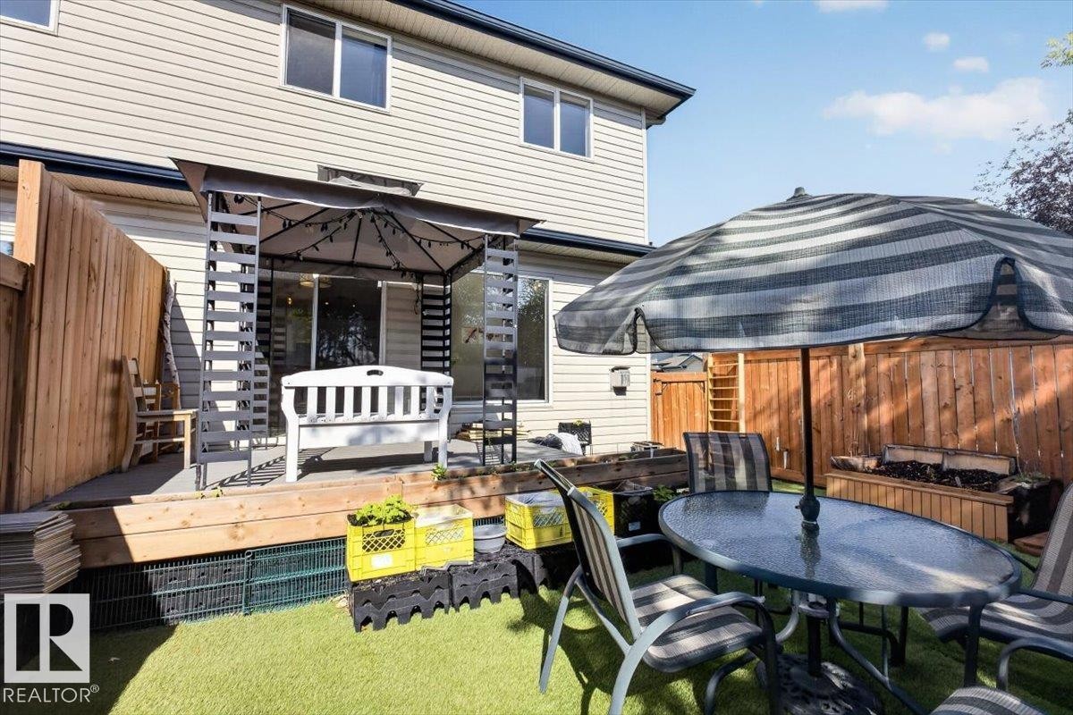 Fenced backyard featuring an artificial turf lawn, a wooden deck, and an attached gazebo - #18 345 Kirkness Rd Nw, Edmonton, AB - Outdoor With Deck Patio Veranda With Exterior