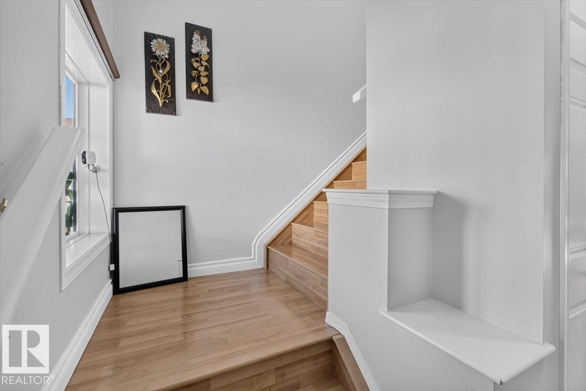 Staircase featuring wood-finish treads and risers, white painted handrail, and baseboards - #18 345 Kirkness Rd Nw, Edmonton, AB - Indoor Photo Showing Other Room