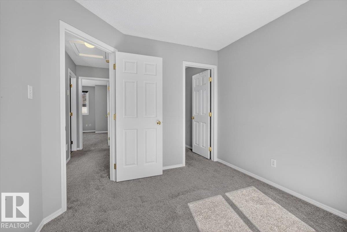 Room featuring gray carpet flooring, light gray wall paint, and white baseboards - #18 345 Kirkness Rd Nw, Edmonton, AB - Indoor Photo Showing Other Room