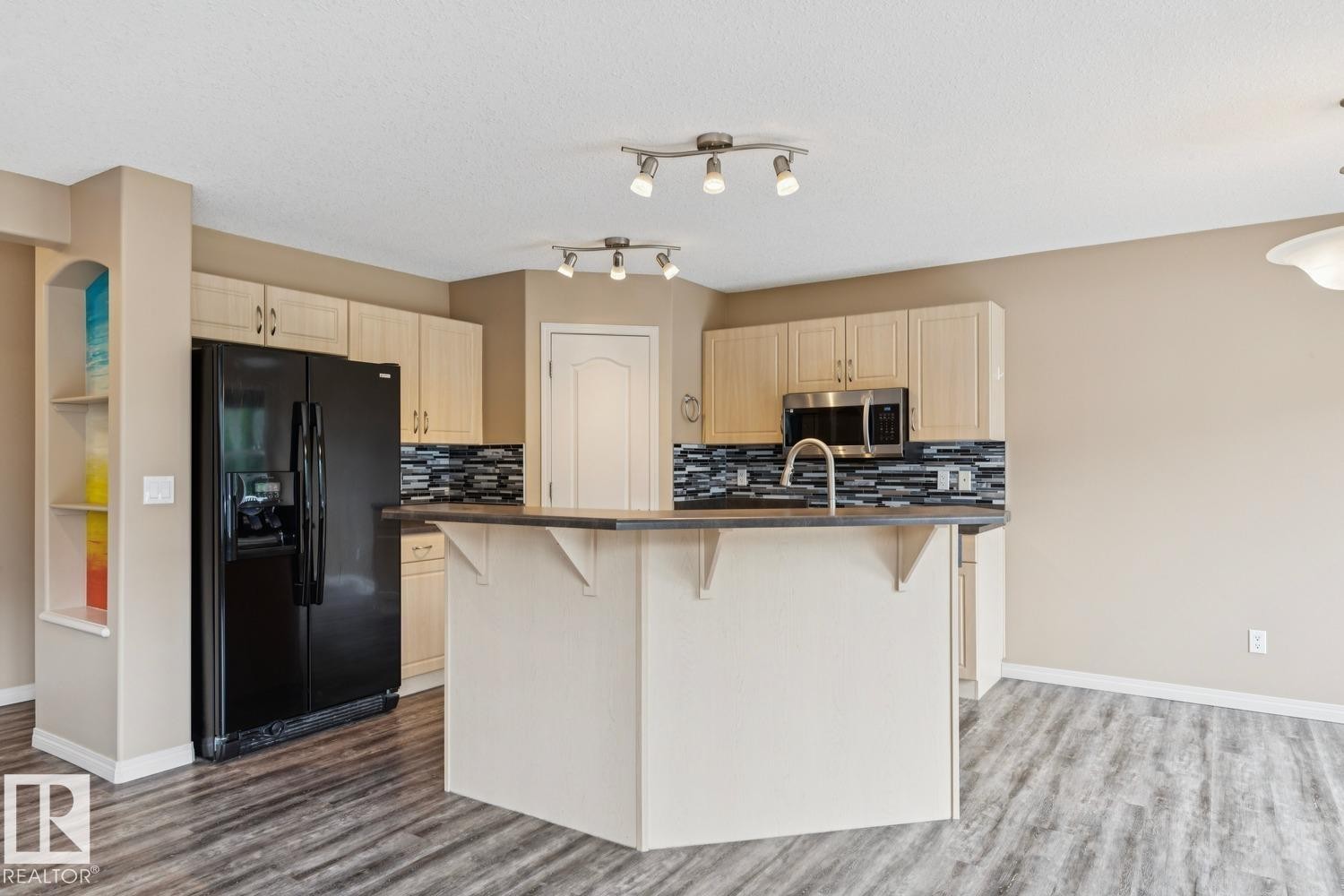 Modern kitchen featuring light wood-finish cabinetry, a black appliance suite, and a textured tile backsplash - 16765 119 Street Nw, Edmonton, AB