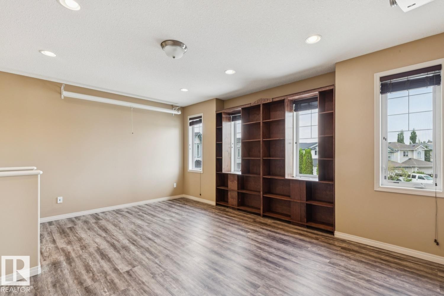 Spacious interior room featuring wood-finish flooring, recessed lighting, and a built-in shelving unit - 16765 119 Street Nw, Edmonton, AB