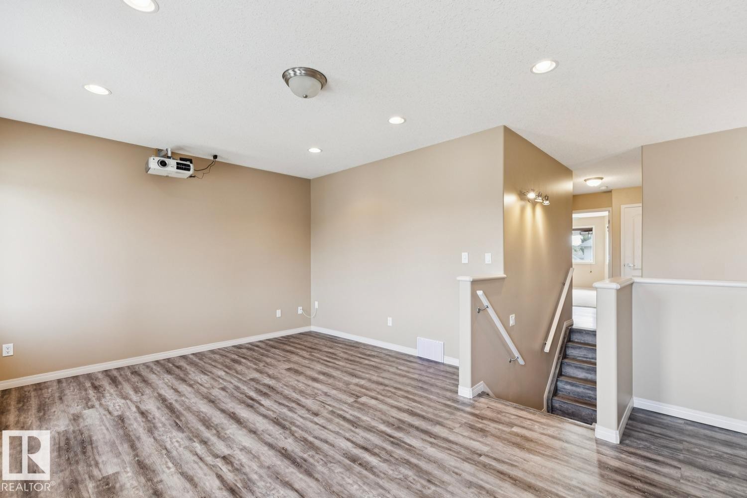 Open concept lower level featuring wood-finish flooring, recessed lighting, and a wall-mounted projector - 16765 119 Street Nw, Edmonton, AB