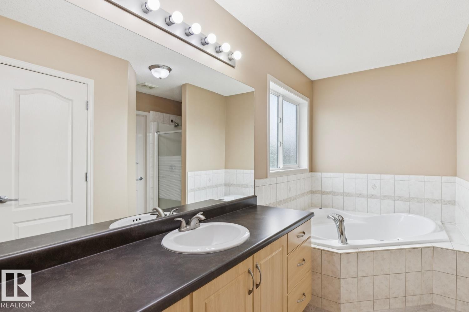 Bathroom featuring a vanity with a single basin sink, laminate countertop, and wood-finish cabinetry - 16765 119 Street Nw, Edmonton, AB