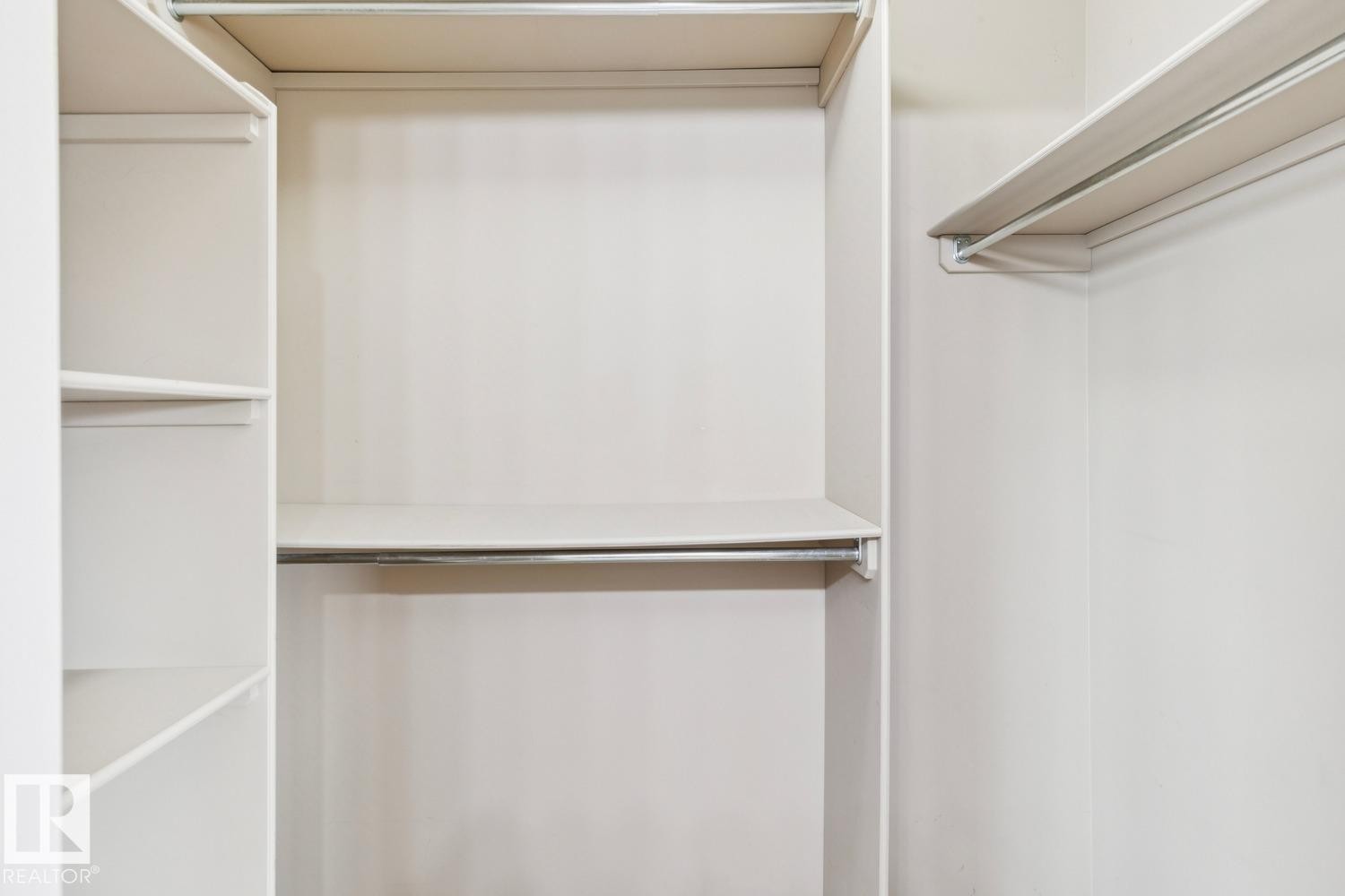Built-in closet system featuring white shelving and chrome hanging rods - 16765 119 Street Nw, Edmonton, AB
