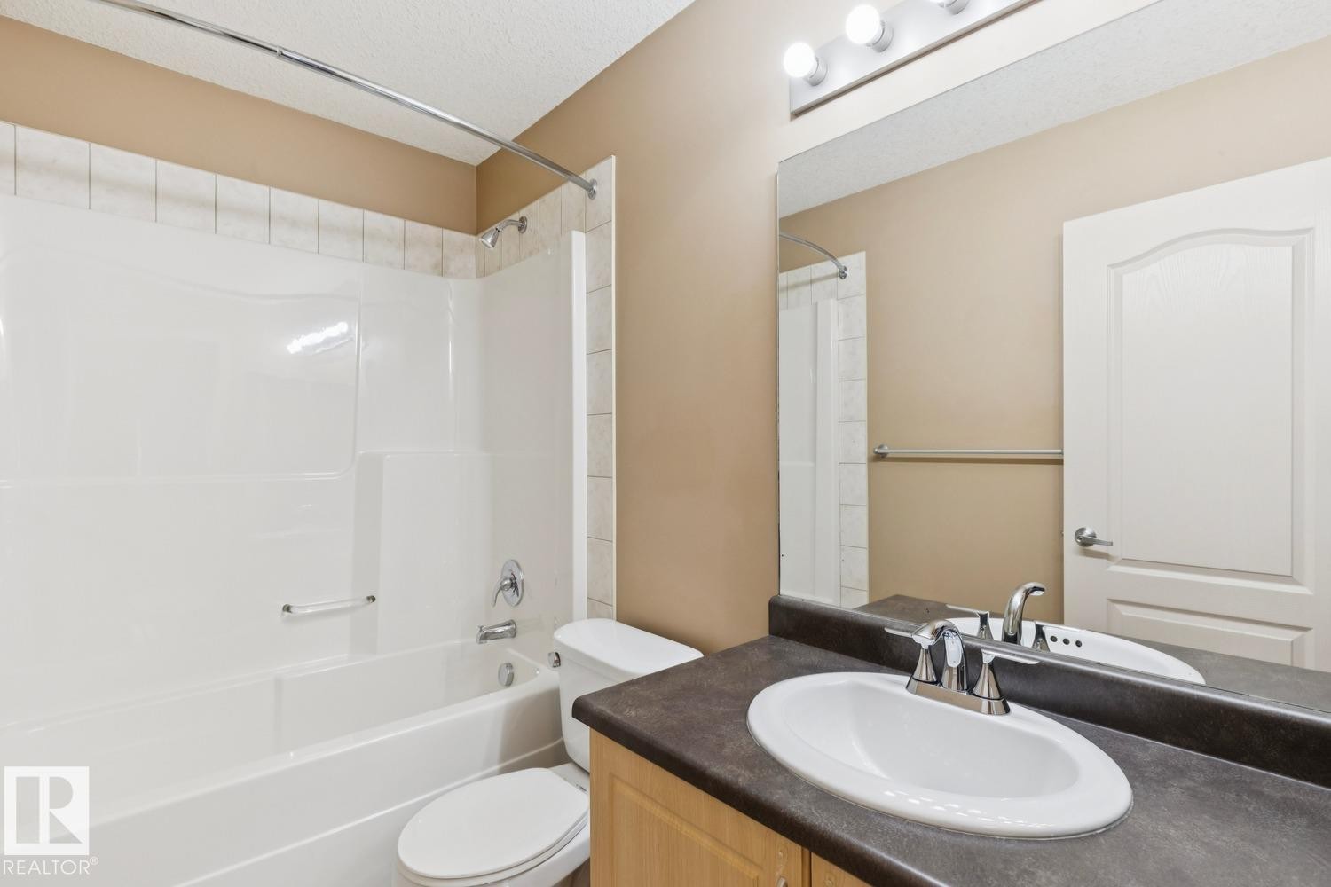 Bathroom featuring a white tub and shower combination with a curved shower rod and decorative tile surround - 16765 119 Street Nw, Edmonton, AB