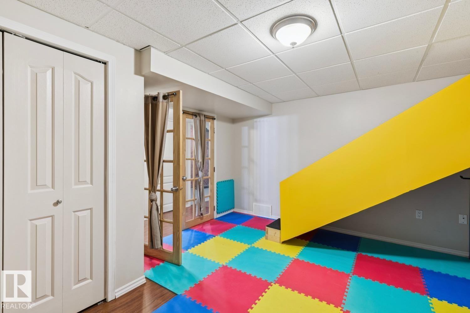 Finished lower level space featuring a bright yellow stairwell wall - 16765 119 Street Nw, Edmonton, AB