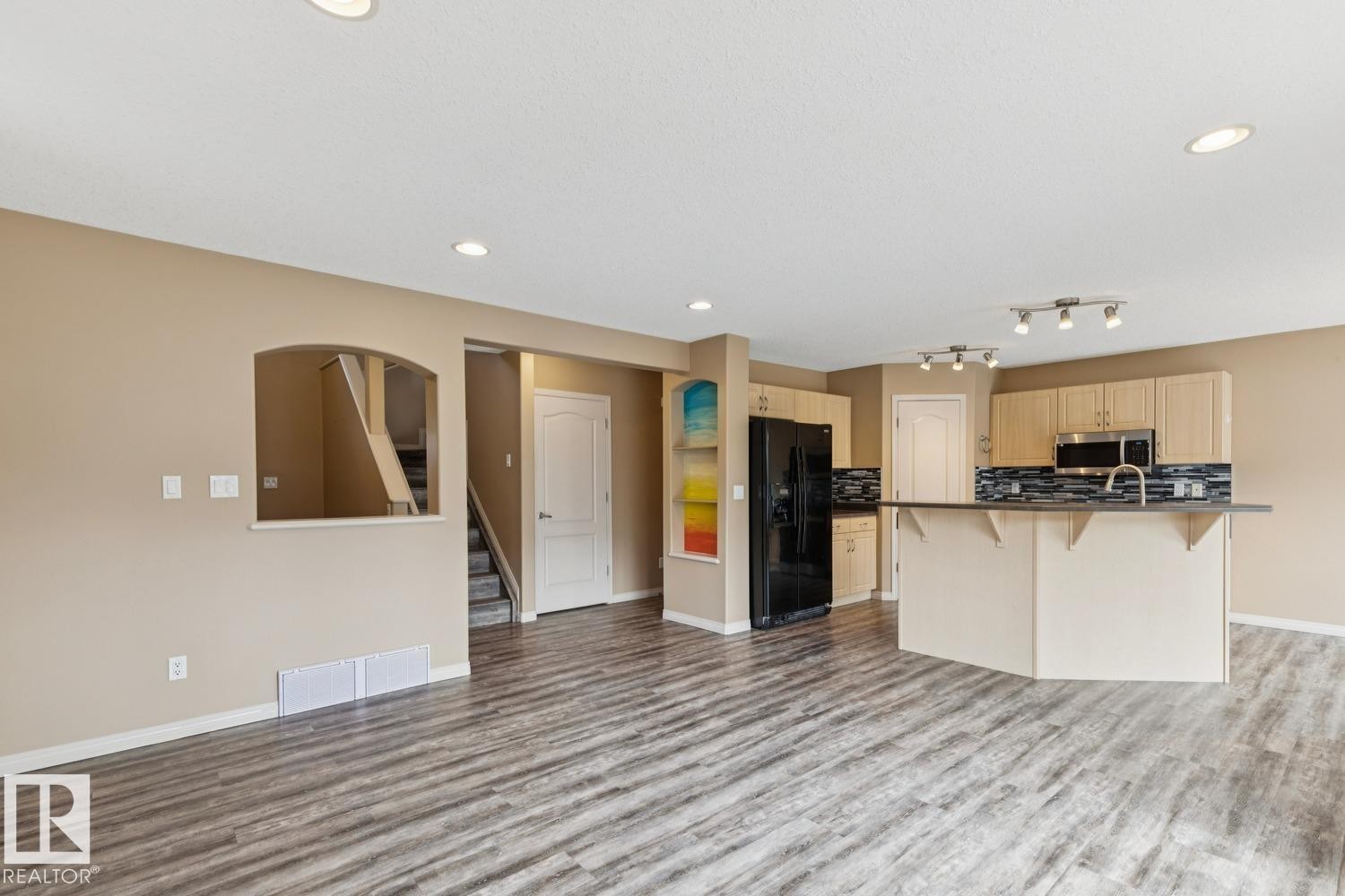 Open-concept living area featuring wood-finish flooring, recessed lighting, and a neutral wall color - 16765 119 Street Nw, Edmonton, AB