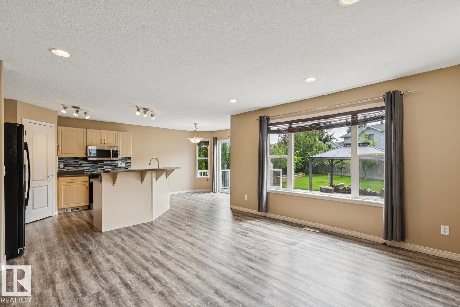 Open-concept living space featuring wood-finish flooring, recessed lighting, and a large picture window - 16765 119 Street Nw, Edmonton, AB