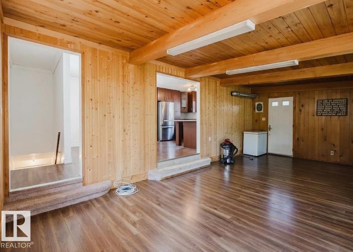 Spacious room featuring wood-panel walls and ceiling with exposed beams - 11115 39A Avenue Nw, Edmonton, AB - Indoor Photo Showing Other Room