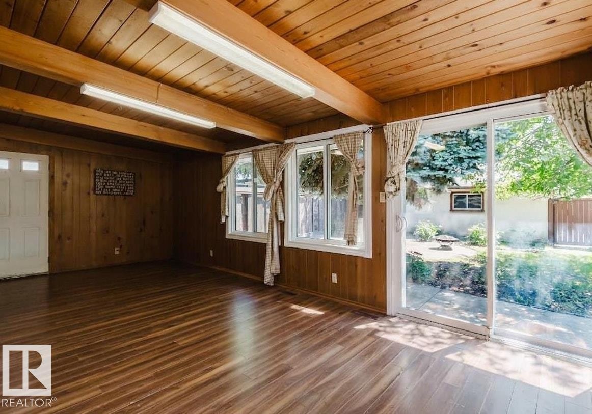 Interior space featuring wood-finish flooring, wood paneling, and an exposed beam ceiling - 11115 39A Avenue Nw, Edmonton, AB - Photo Showing Other Room