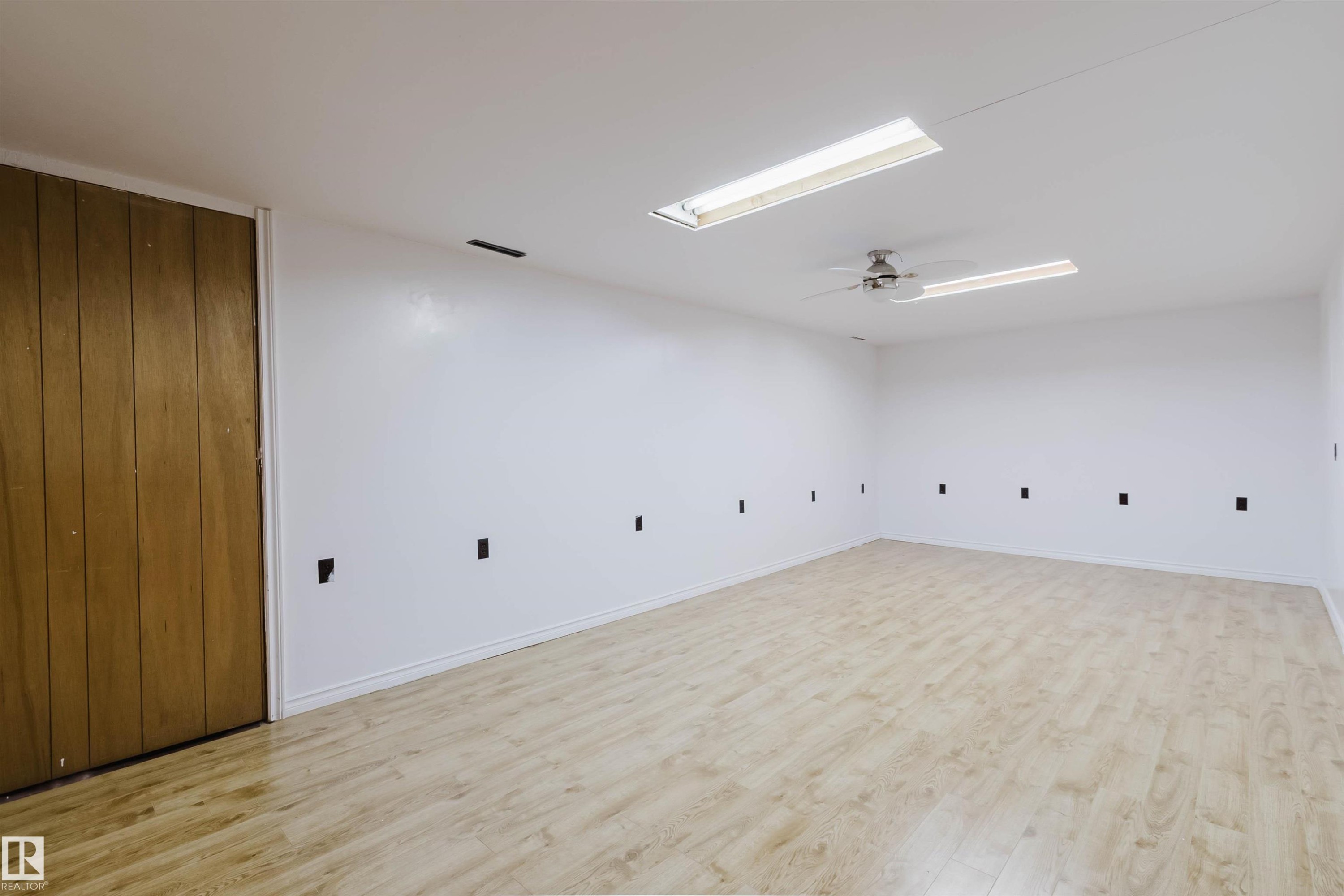 Spacious room featuring wood-finish flooring, white walls, and a ceiling fan - 11115 39A Avenue Nw, Edmonton, AB - Indoor Photo Showing Other Room