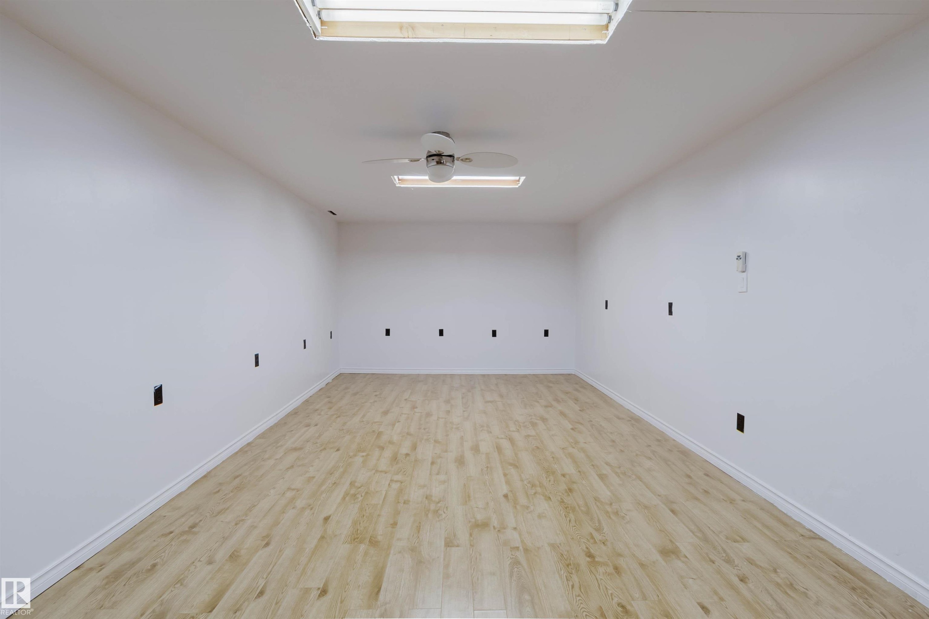 Spacious room featuring light wood-finish flooring, white walls, and white baseboards - 11115 39A Avenue Nw, Edmonton, AB - Indoor Photo Showing Other Room