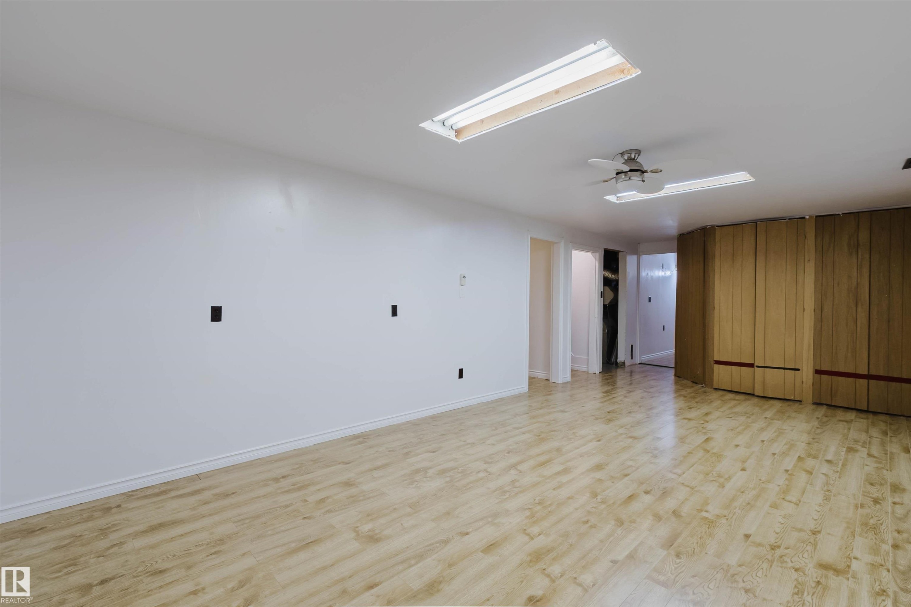 Spacious room featuring light wood-finish flooring, white walls, and a ceiling fan - 11115 39A Avenue Nw, Edmonton, AB - Indoor Photo Showing Other Room