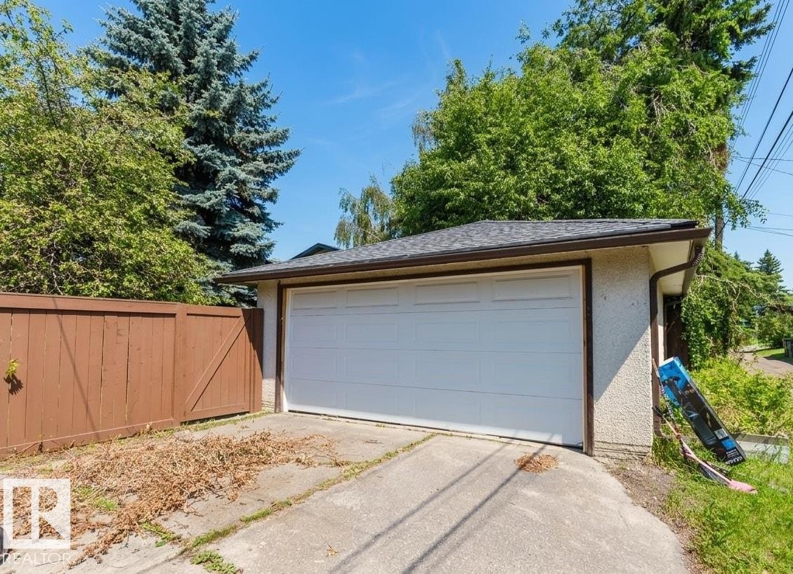 Detached garage featuring a white panel door, concrete driveway, and asphalt shingle roof - 11115 39A Avenue Nw, Edmonton, AB - Outdoor
