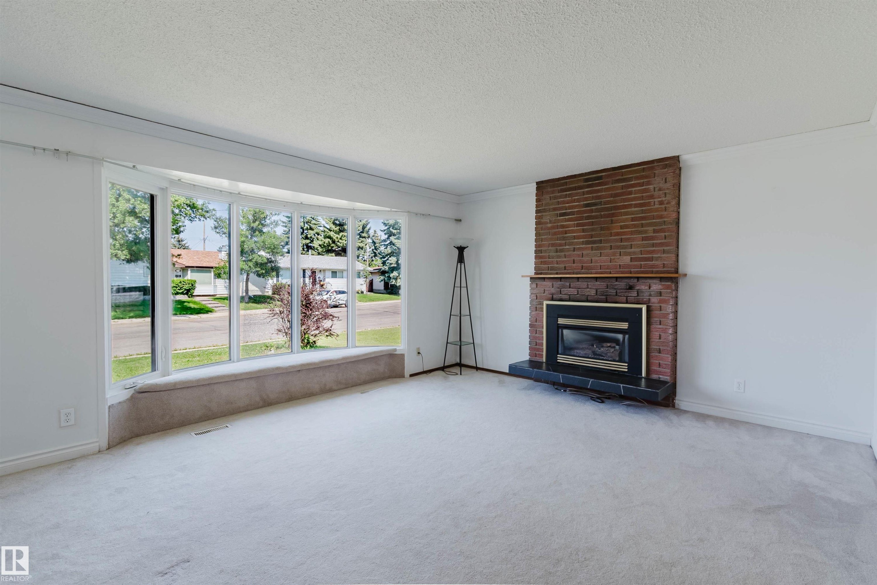 Bright living space featuring a wide bay window with an integrated window seat - 11115 39A Avenue Nw, Edmonton, AB - Indoor Photo Showing Living Room With Fireplace