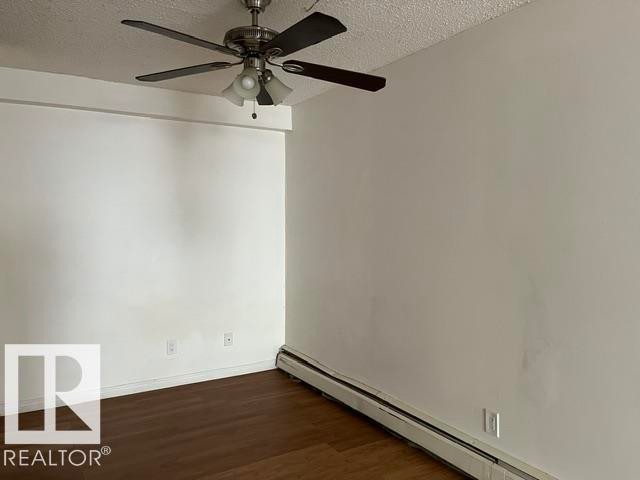 Spacious room featuring wood-finish flooring and a ceiling fan with integrated lighting - #205 10740 105 St Nw, Edmonton, AB - Indoor Photo Showing Other Room