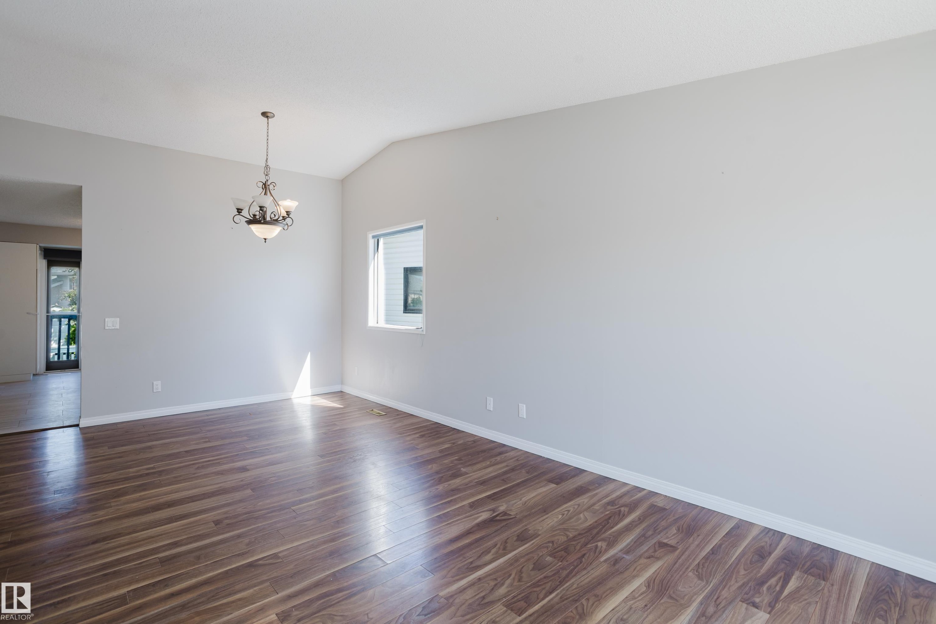 Spacious interior room featuring rich wood-finish flooring, a vaulted ceiling, and a decorative chandelier - 337 Pearson Crescent Nw, Edmonton, AB - Indoor Photo Showing Other Room