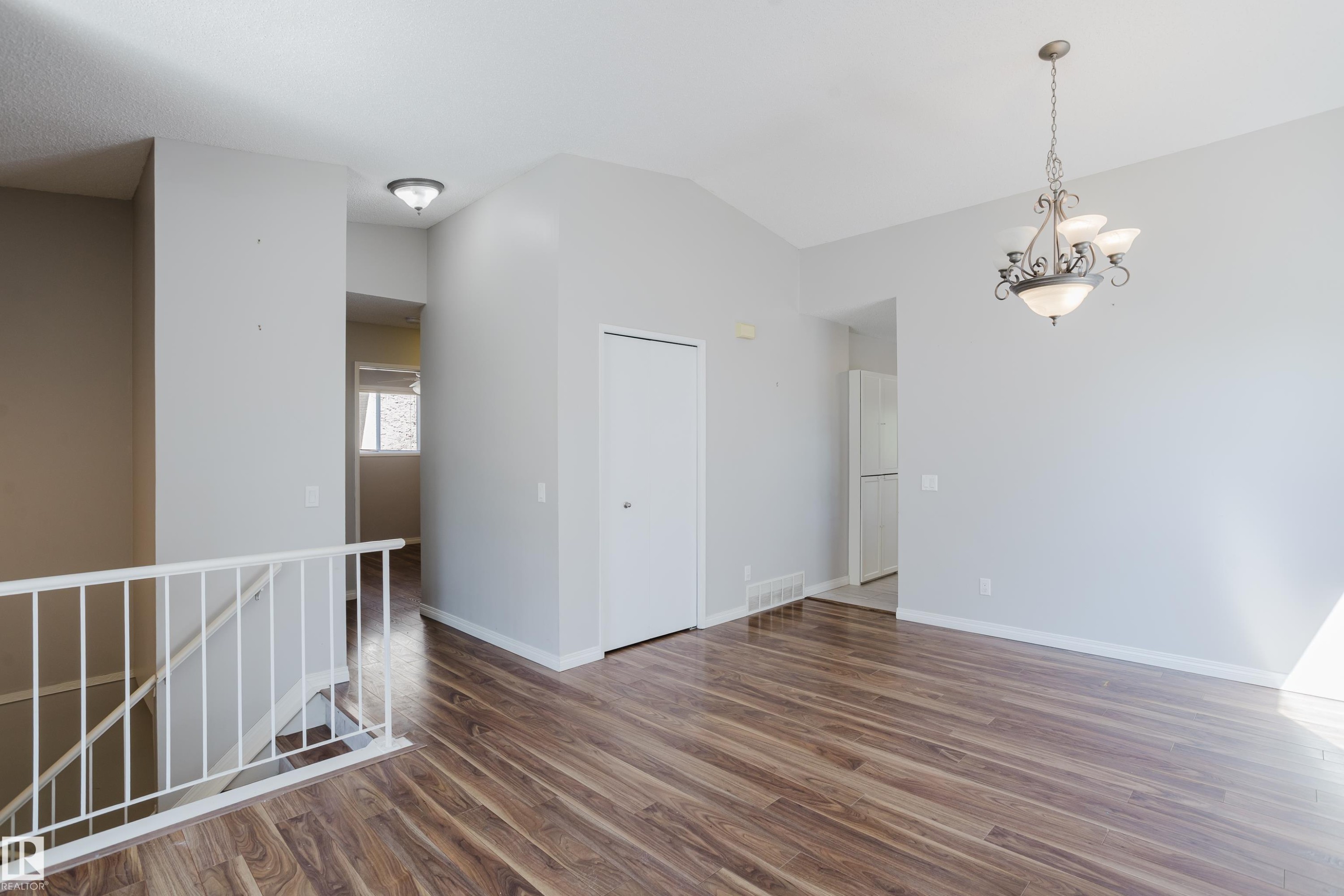 Open-concept living space with vaulted ceilings, wood-finish flooring, a decorative chandelier, and white baseboards - 337 Pearson Crescent Nw, Edmonton, AB - Indoor Photo Showing Other Room
