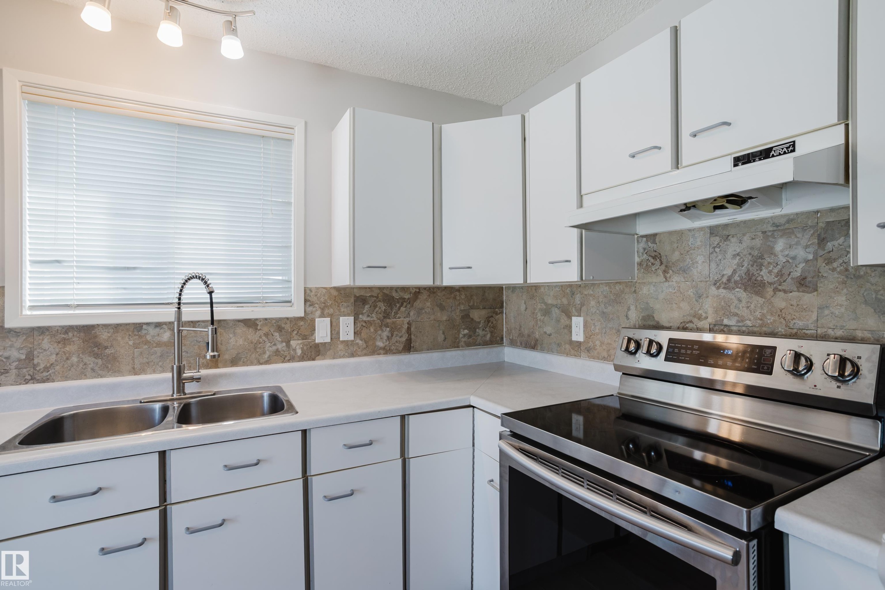Kitchen featuring white cabinetry, light-toned countertops, a stainless steel electric range, and a dual basin sink with a gooseneck faucet - 337 Pearson Crescent Nw, Edmonton, AB - Indoor Photo Showing Kitchen With Double Sink