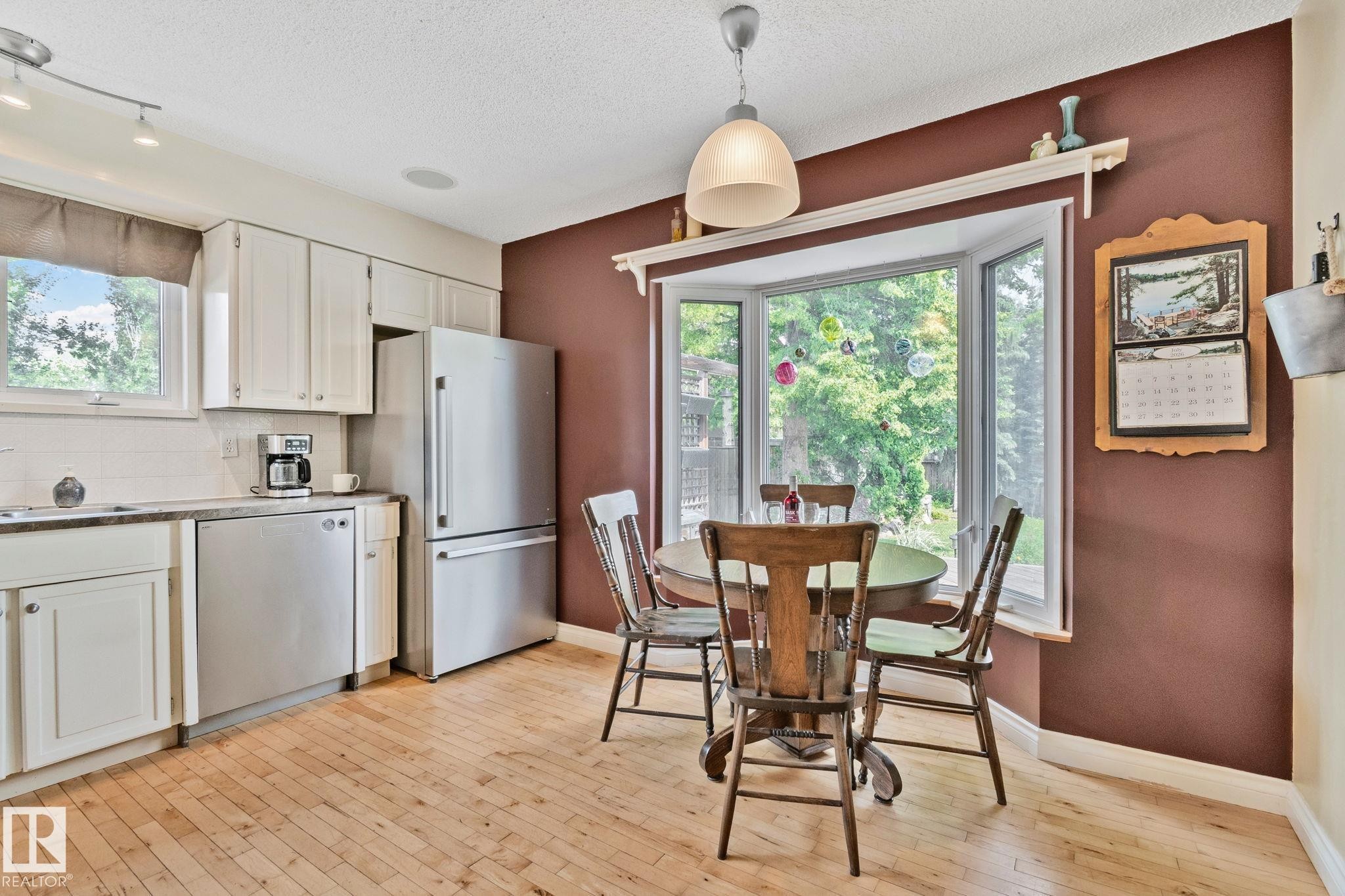 Kitchen featuring wood-finish flooring, white cabinetry, and a subway tile backsplash - 7306 21 Avenue Nw, Edmonton, AB - Indoor