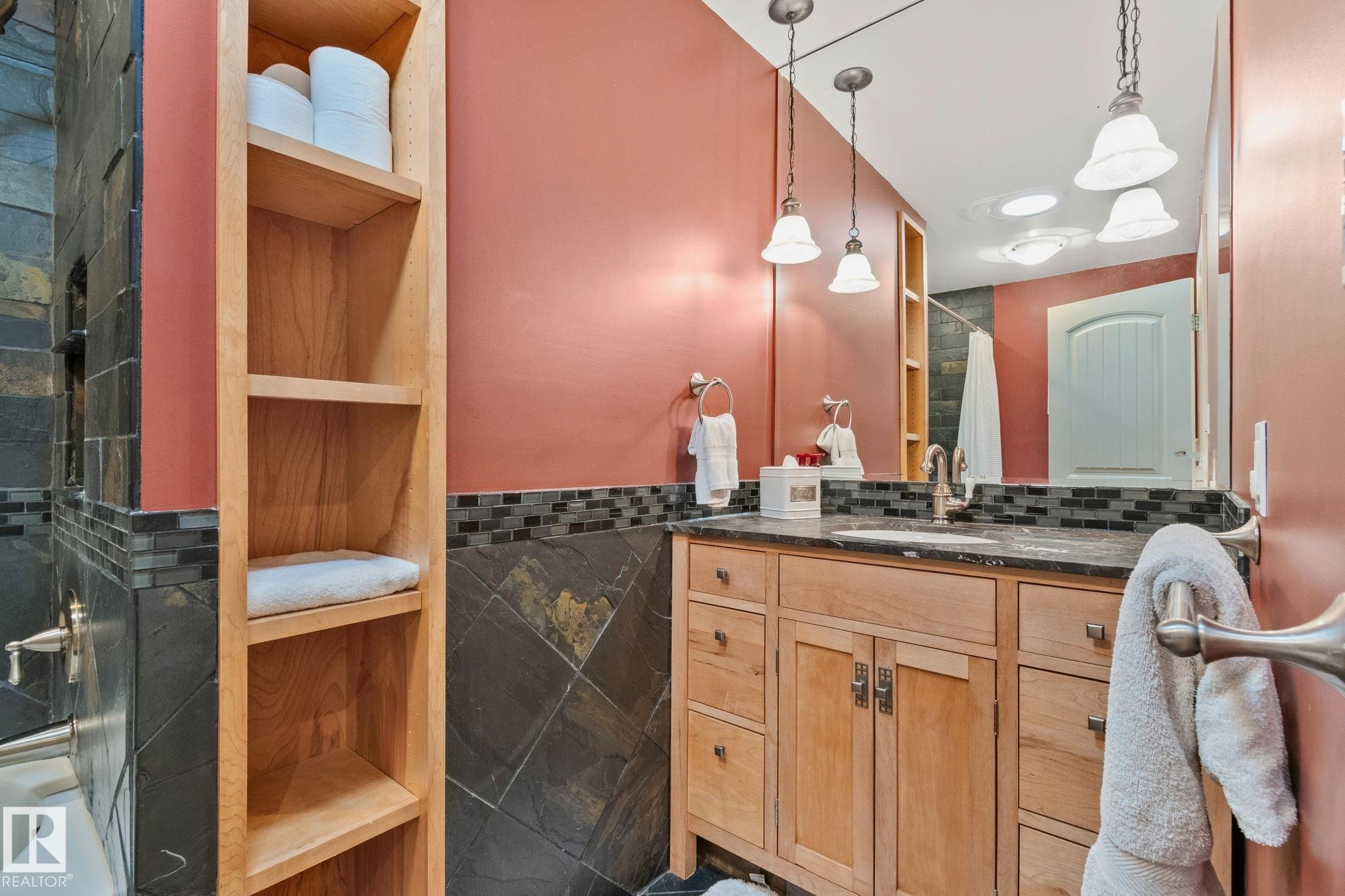 Vanity with wood cabinetry, dark countertop, and undermount sink - 7306 21 Avenue Nw, Edmonton, AB - Indoor Photo Showing Bathroom